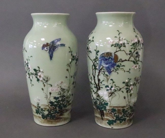 Null 日本，约1900年

一对多色珐琅彩的瓷质柱形花瓶，绿色背景上绘有鸟类和樱花树。

高32厘米；直径14.5厘米