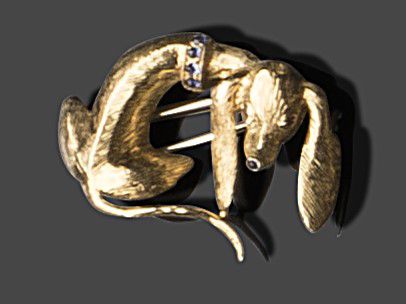 Null 18K（750）黄金胸花夹，以一只狗为主题。眼睛、衣领和鼻子都镶嵌着凸圆形蓝宝石或红宝石。
高 : 3,5 cm
毛重 : 10,00 g