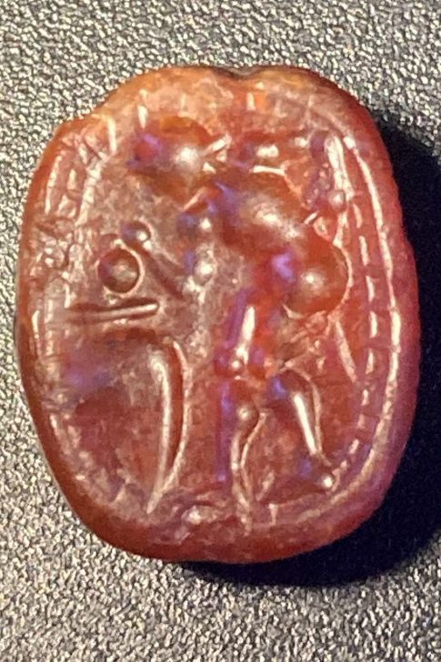 Null 
红玉髓刀疤，底部刻有一个裸体萨提尔从大罐子里取酒的场景。罗马时期，公元2世纪，1X0.7厘米，正面有小缺口