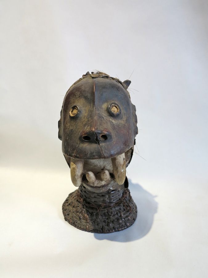 Null 变形徽章面具，面部覆盖着羚羊皮，张着嘴，站在一个圆柱形的柳条底座上。 
尼日利亚，Ekoi/Ejagham族群，高30厘米。