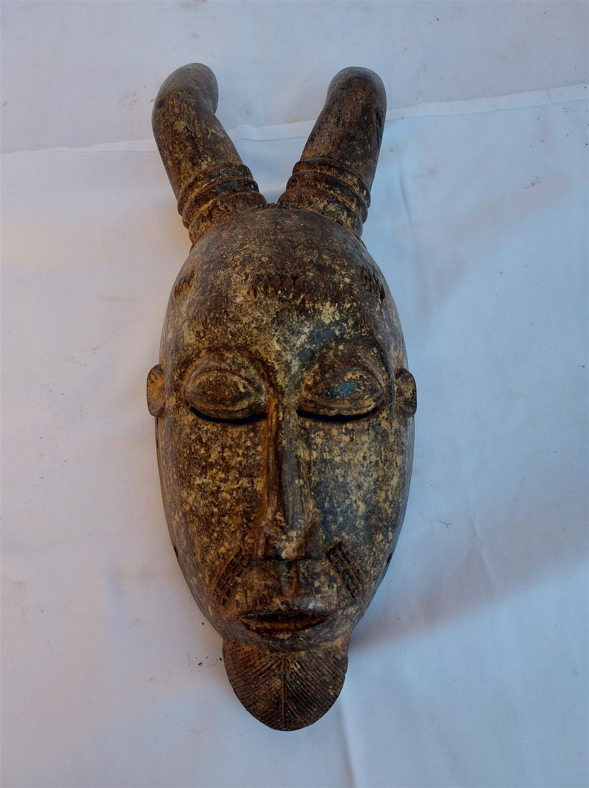 Null Masque à sujet de visage surmonté de cornes, bois sculpté. Long. 42cm