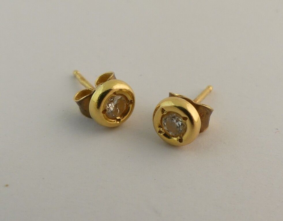 Null Pair of yellow gold stud earrings each with a TM diamond. PB. 1.2g.