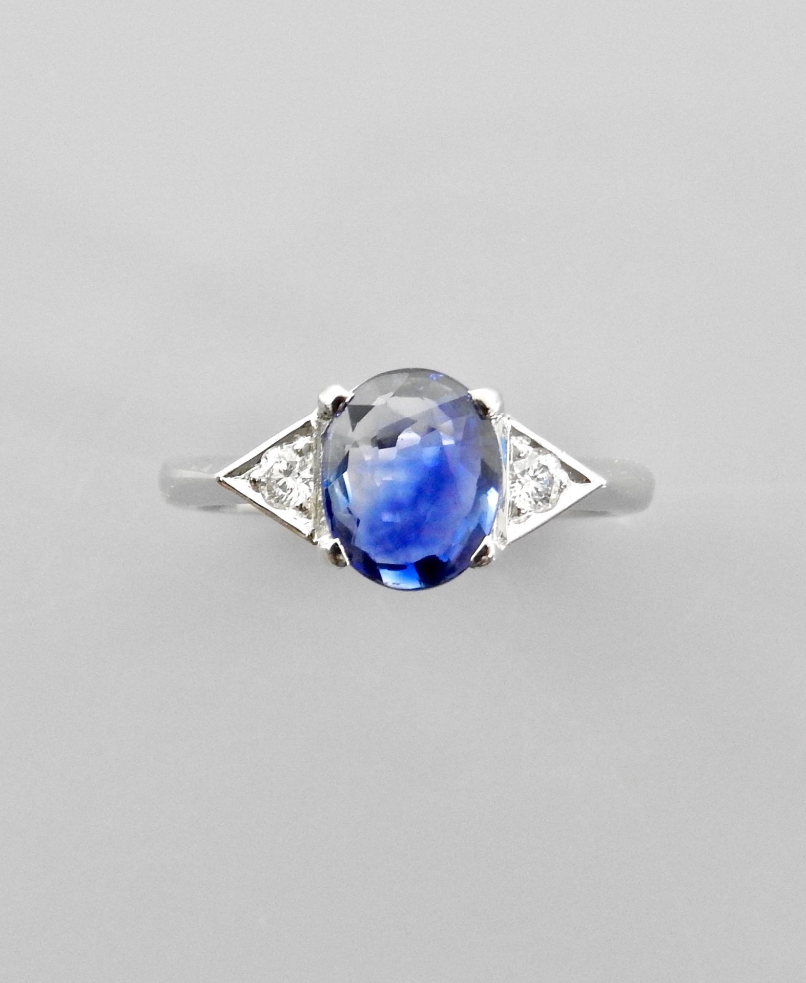 Null 白金戒指，750毫米，镶有一颗美丽的椭圆形蓝宝石，重2.30克拉，来自锡兰，有两颗钻石组成两个三角形图案，尺寸：54，重量：5.15克。