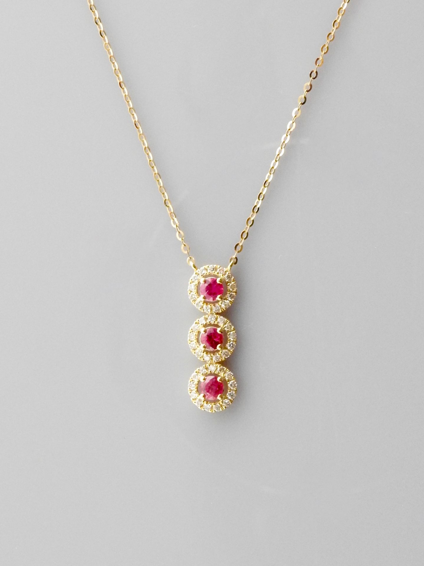 Null 链条和吊坠绘制了三个玫瑰金菱形，750毫米，每一个都在一圈钻石中装饰了一颗红宝石，长度为2厘米，弹簧环扣，可调节长度为42厘米，重量：1.7克。