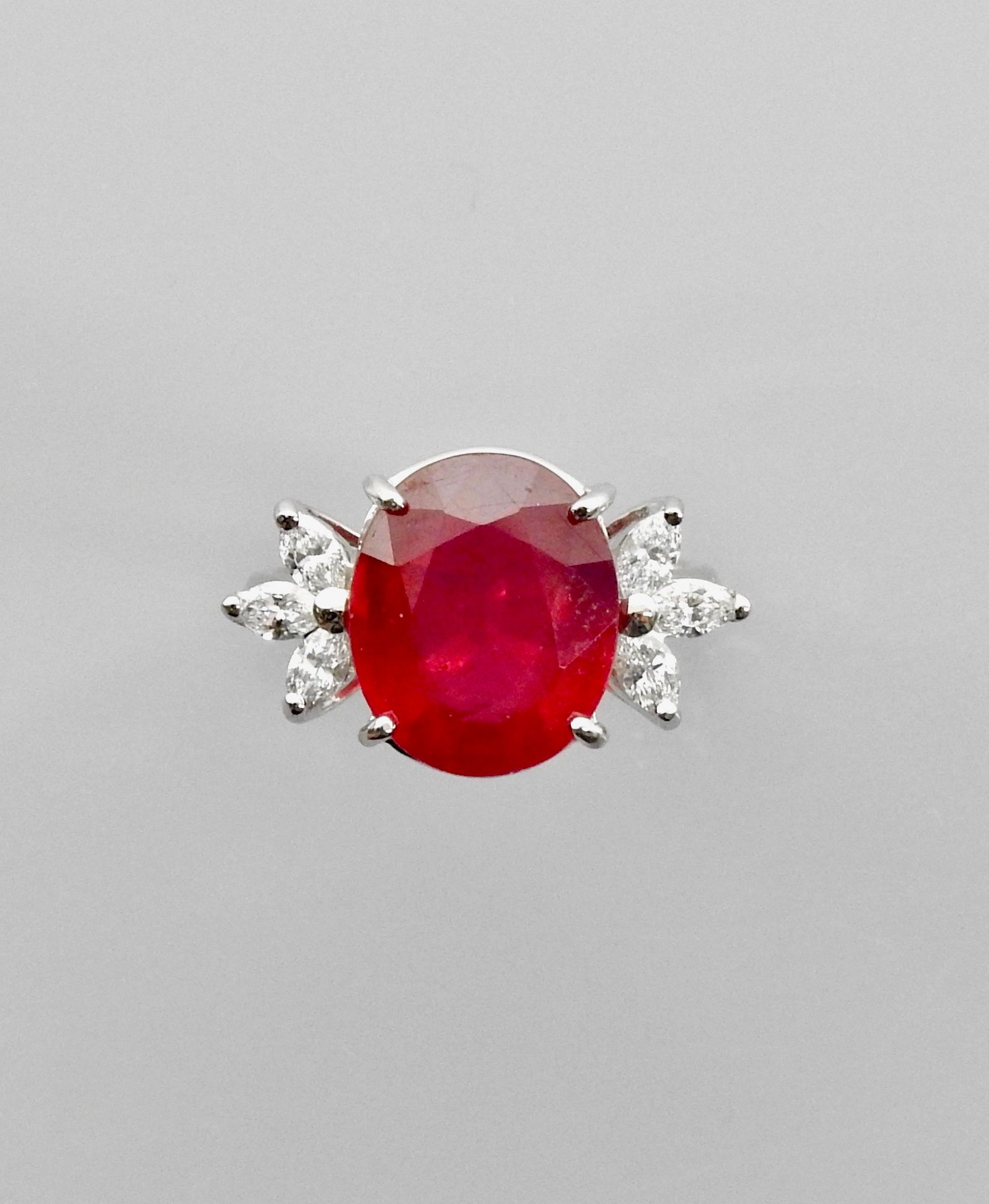 Null 白金 "花 "戒指，750毫米，镶有一颗经处理的椭圆形红宝石，重7.80克拉，以及总重0.50克拉的脐形切割钻石，尺寸：54/55，重量：6克。