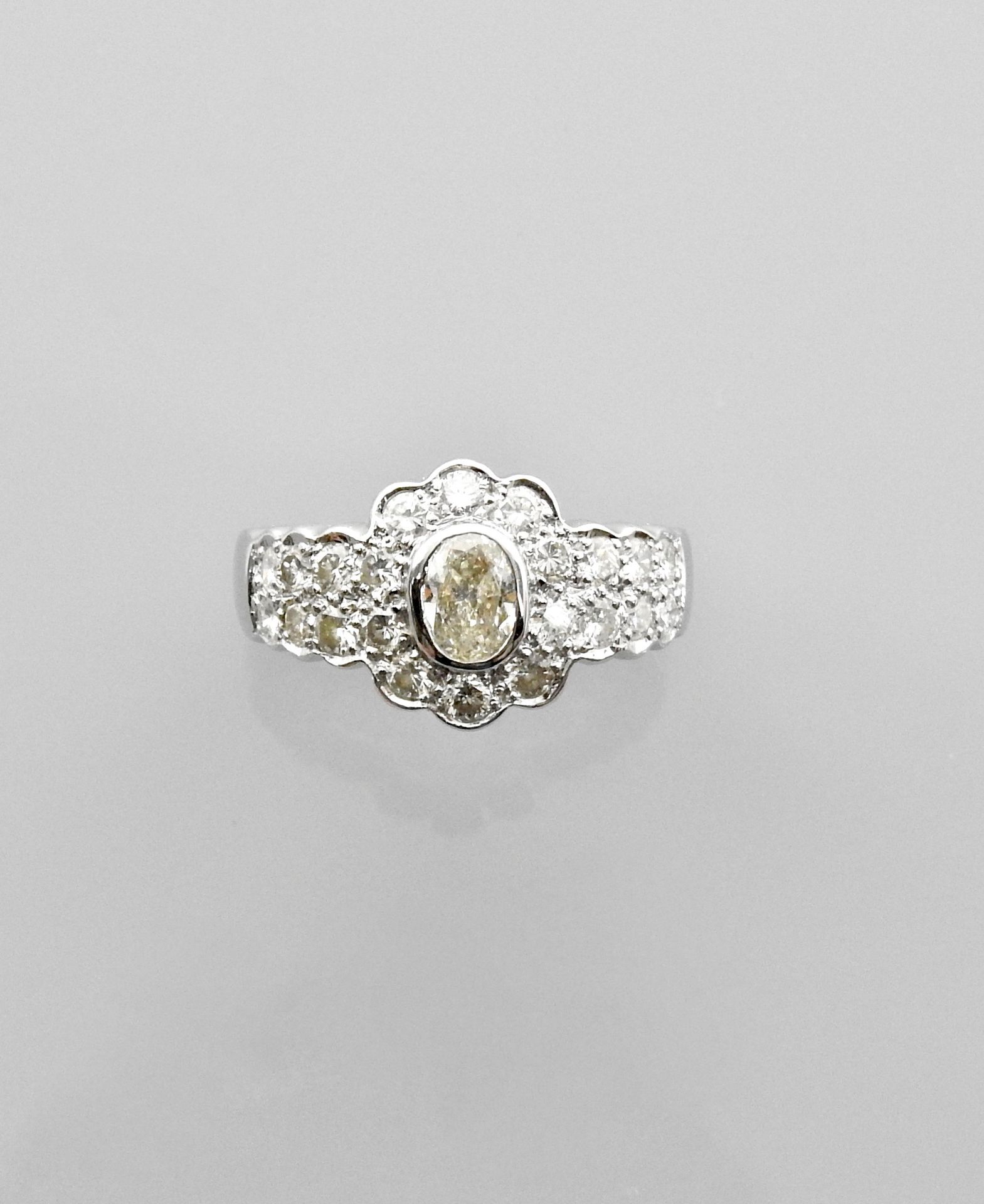 Null Bague dessinant une fleurette d'or gris, centrée d'un diamant ovale pesant &hellip;