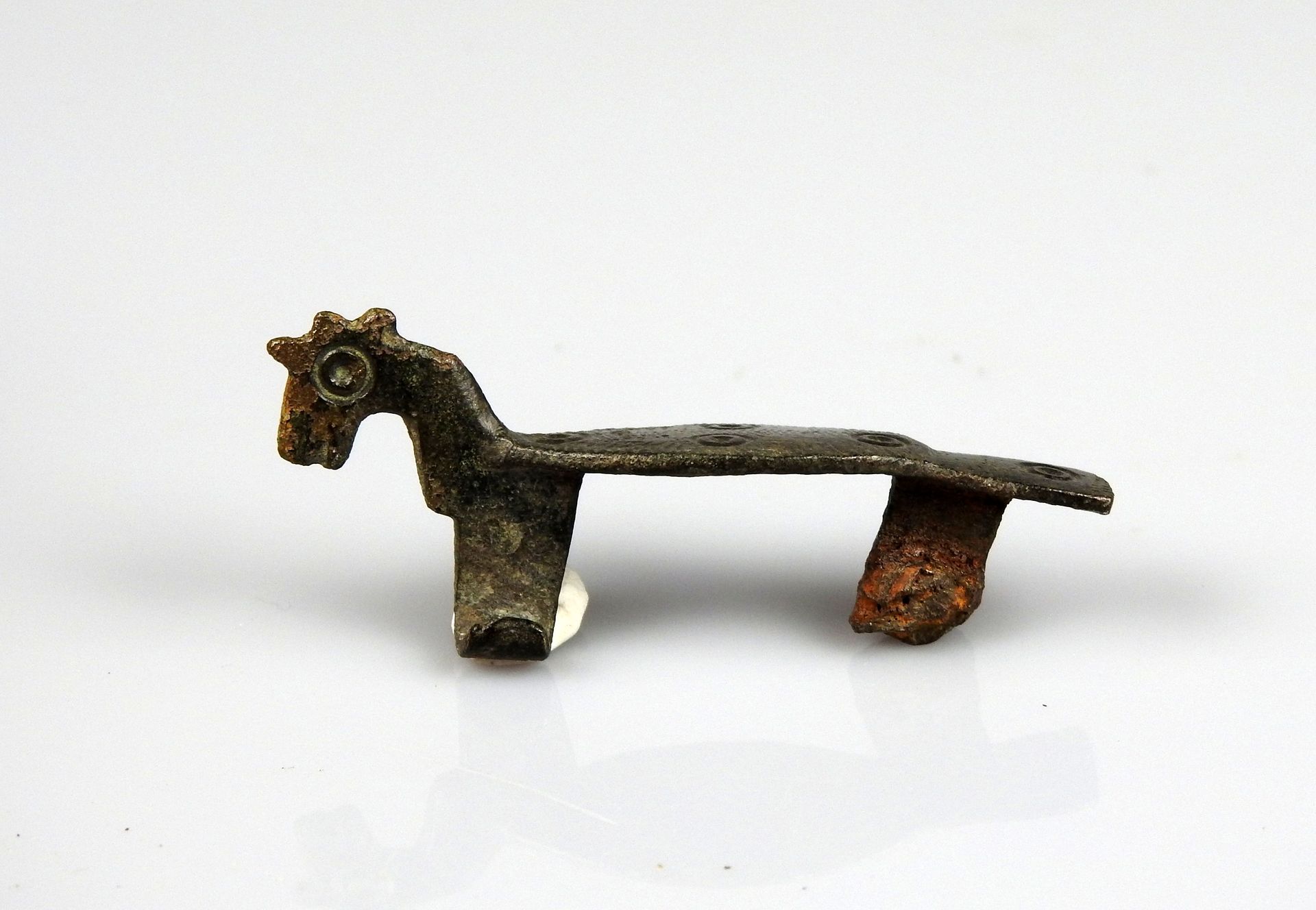 Null Scharnierfibel mit Darstellung eines stilisierten Pferdes

Bronze 4,7 cm

R&hellip;