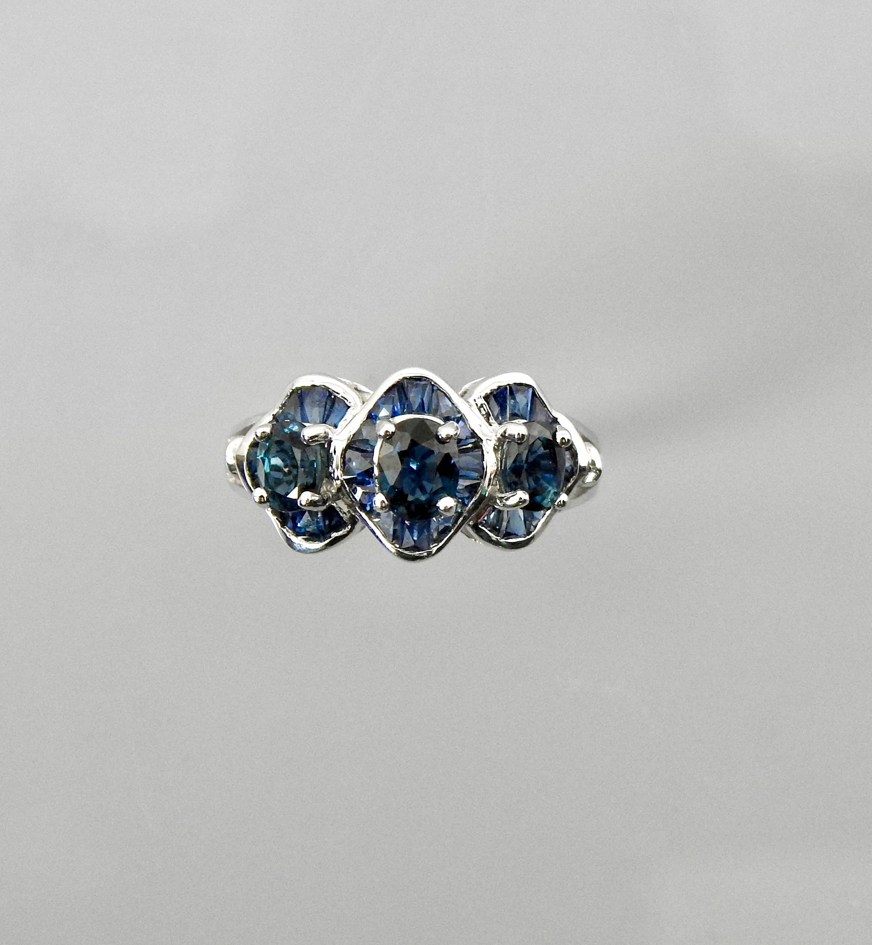 Null 白金戒指，在两颗钻石之间绘制了三个装饰有椭圆形和校准蓝宝石的图案，尺寸：55，重量：4.26g。