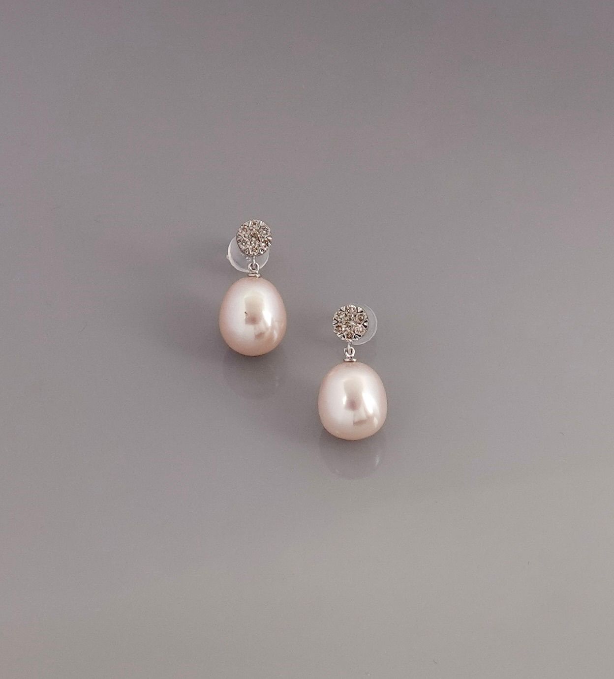 Null 白金耳环，750毫米，镶有一朵钻石花，每朵钻石花上有一颗椭圆形的珍珠，圆柱形硅胶扣，重量：2.6克。