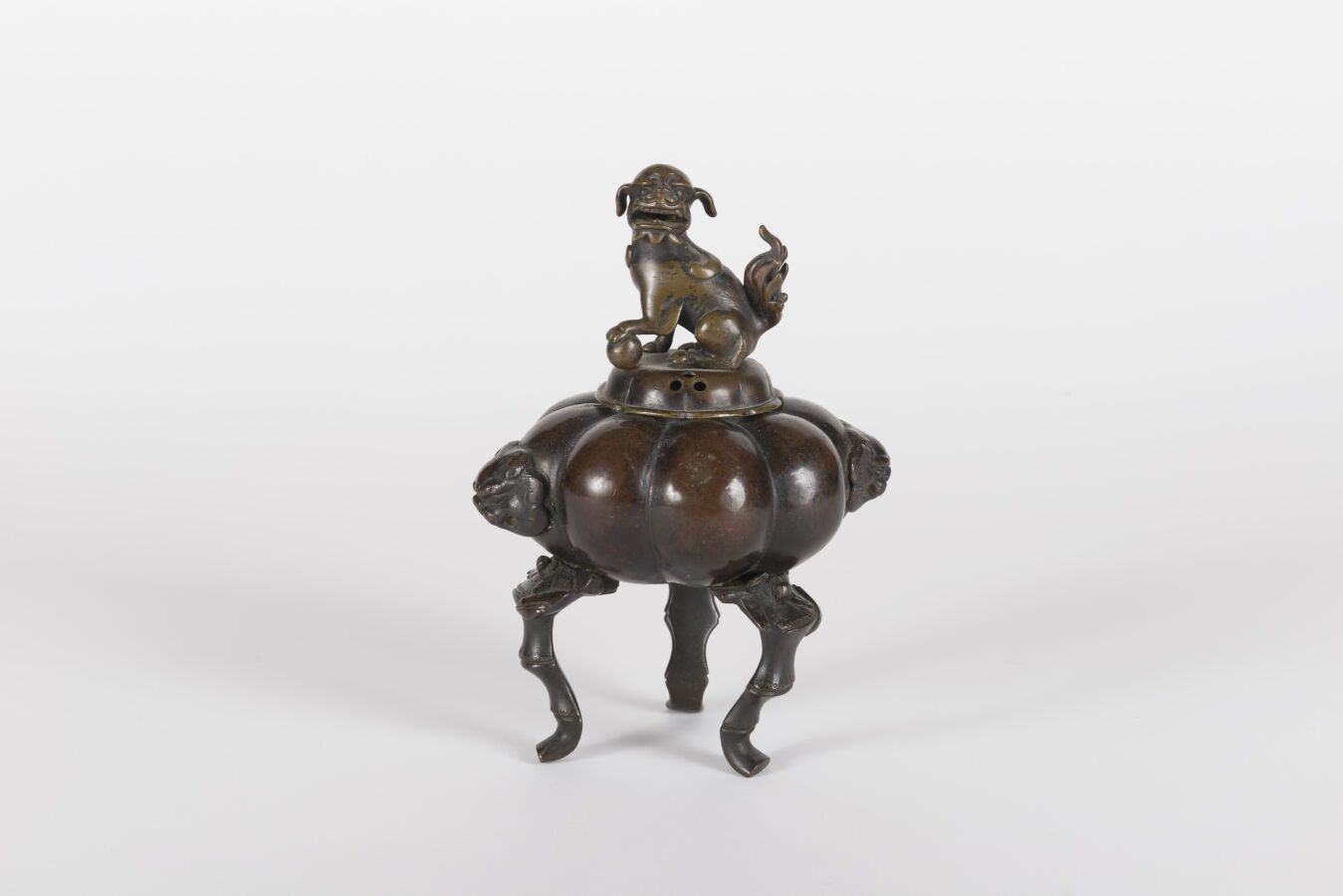 Null 青铜鼎香炉
中国，19世纪
浅裂的器身，靠在三个竹脚上，器身两边的两个狮子头形成把手，盖子上有一只佛狗；相关的盖子 
H.20.5厘米
