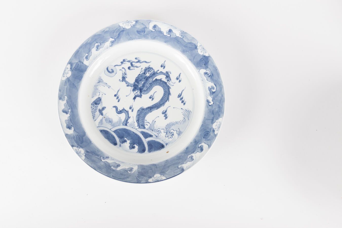 Null 青花瓷小碟
中国，康熙时期 (1662-1722)
饰有龙和鲤鱼从汹涌的波涛中升起，边缘饰有波浪；破裂
尺寸：27厘米