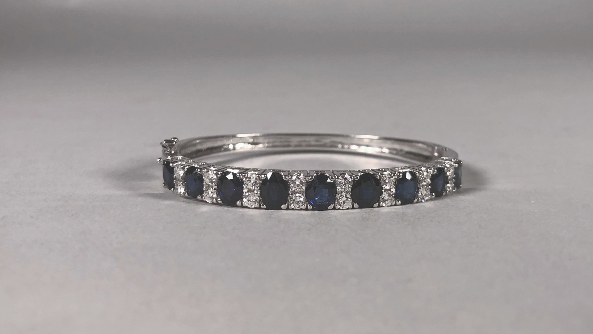 Null 18K（750°/°）白金铰链手镯，镶嵌九颗蓝宝石（约0.6克拉），与八排两颗明亮式切割钻石（2.7毫米，约0.08克拉）交替。

内宽：5厘米 - &hellip;