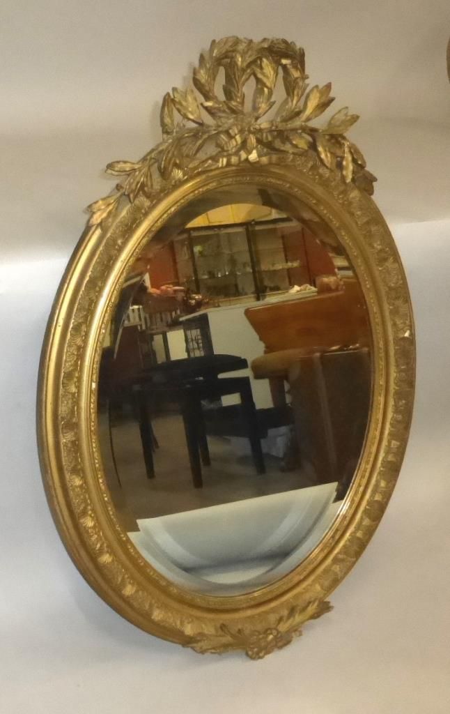 Null Miroir ovale en bois et stuc doré à décor de lauriers et rubans.

XIXe sièc&hellip;
