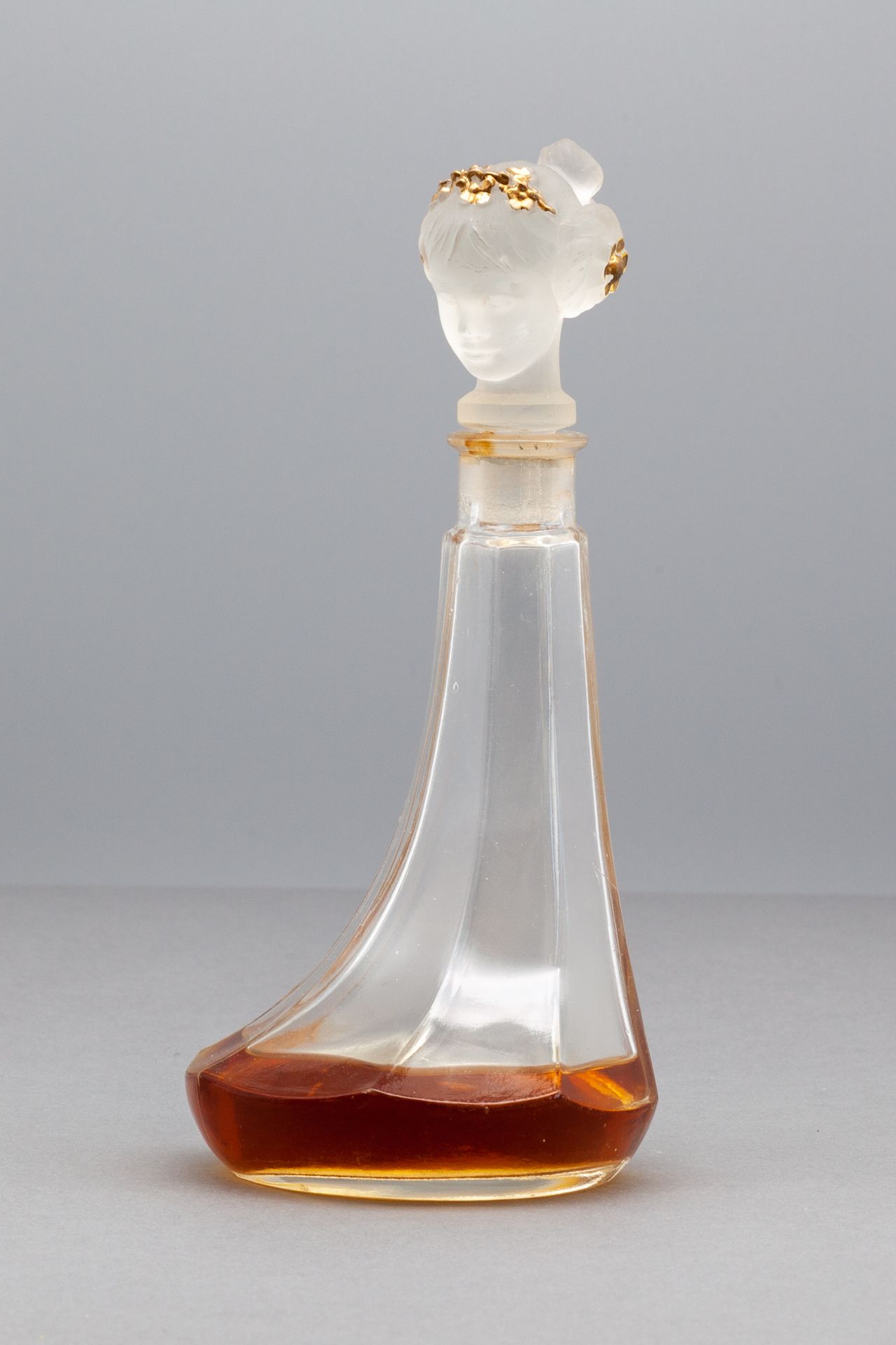 LUBIN- VIARD "MAGDA" 玻璃瓶，不对称的瓶身，浮雕和磨砂的瓶塞，显示一个戴着金色皇冠的年轻女孩的头。1921年期间。高17厘米
