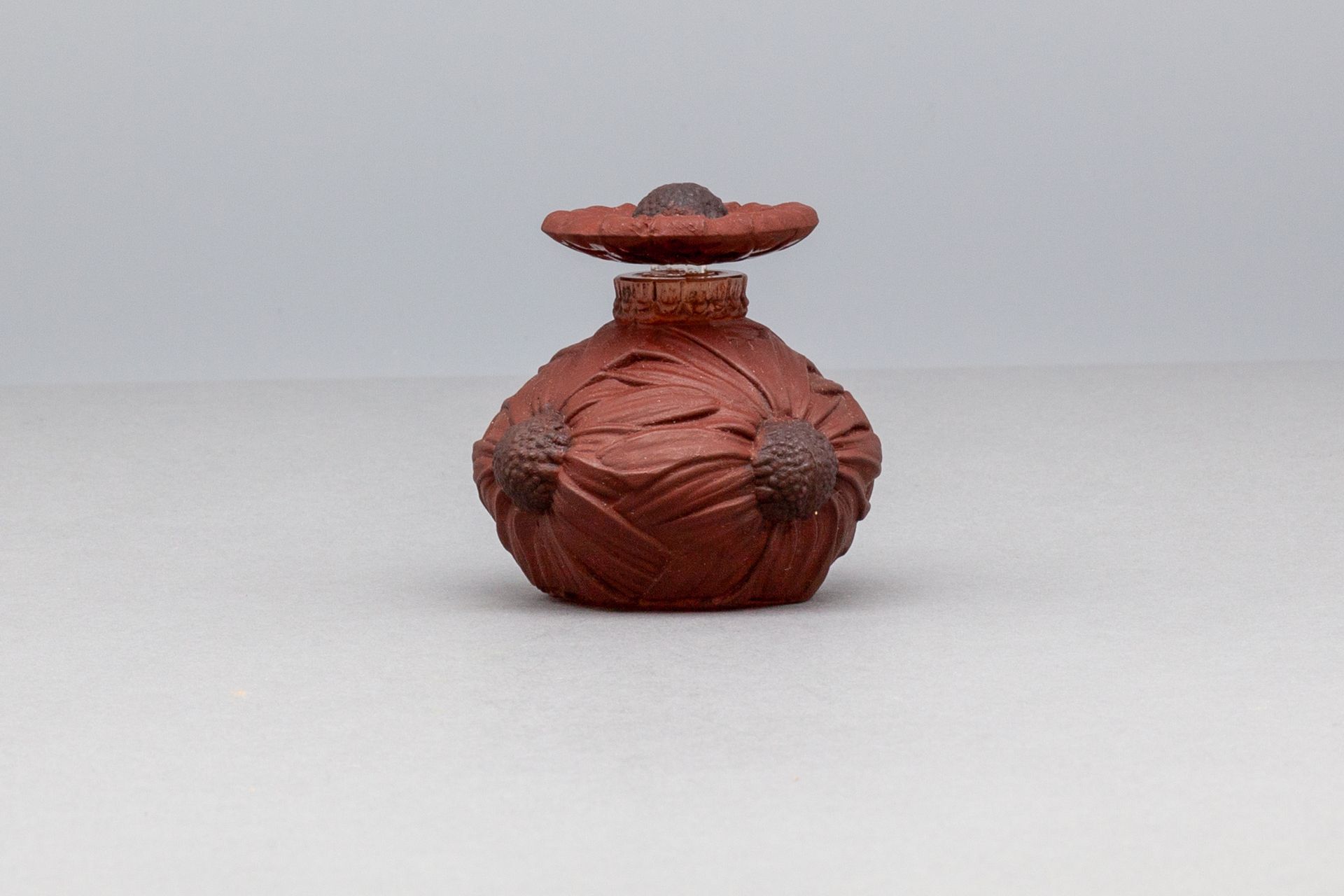 CLAMY "ANTHEMIS" 无色磨砂玻璃瓶，球状，有四朵花。花瓣形状的瓶塞，带有棕色和黑色的铜锈。 底部的标题是L.GAILLARD。1914年期间。高5&hellip;