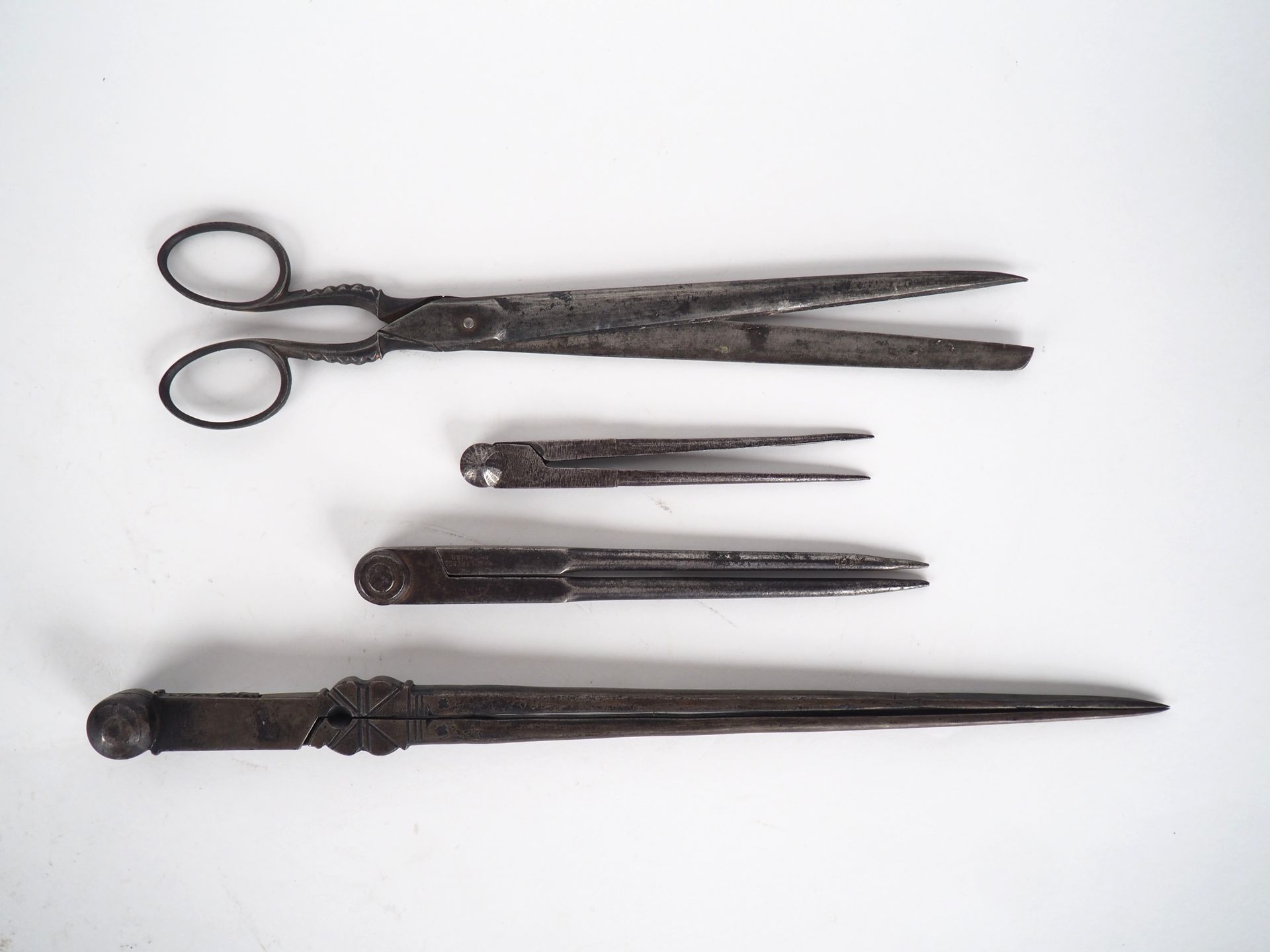 Null 3 diversi compassi antichi in ferro battuto e un paio di forbici.