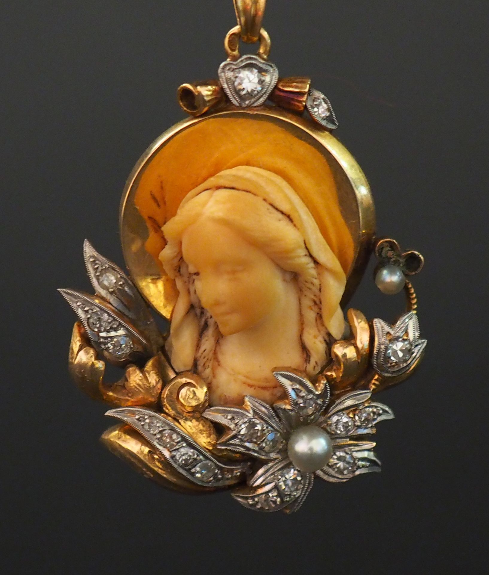 Null 一件拿破仑三世的黄金、象牙、钻石和珍珠吊坠，描绘了光环下的圣母，周围是鲜花和绿叶。

H.4厘米

重量如故。15,58 g

(小的缺乏)