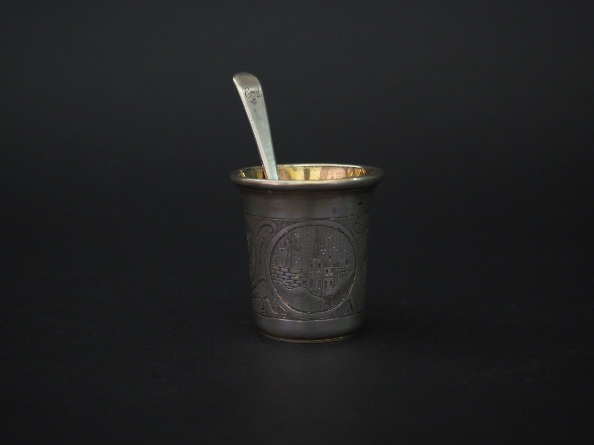 Null 一个小型的俄罗斯银质高脚杯，装饰着卷轴和风景的储备。

日期为1860年。

有图案的。

H.5厘米

一个小的俄罗斯银和vermeil勺子。

有&hellip;