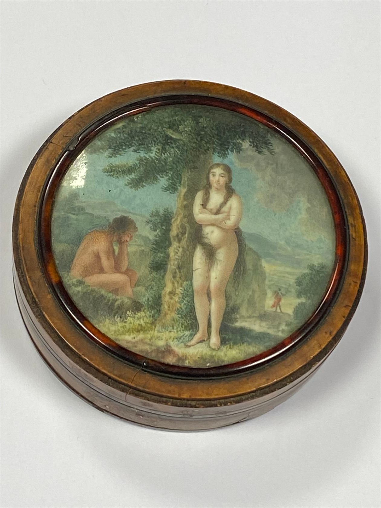 Null 胡桃木毛刺贴面的盒子，盖子上装饰着象牙上的微型画，代表亚当和夏娃从天堂出来。19世纪初。直径8厘米。