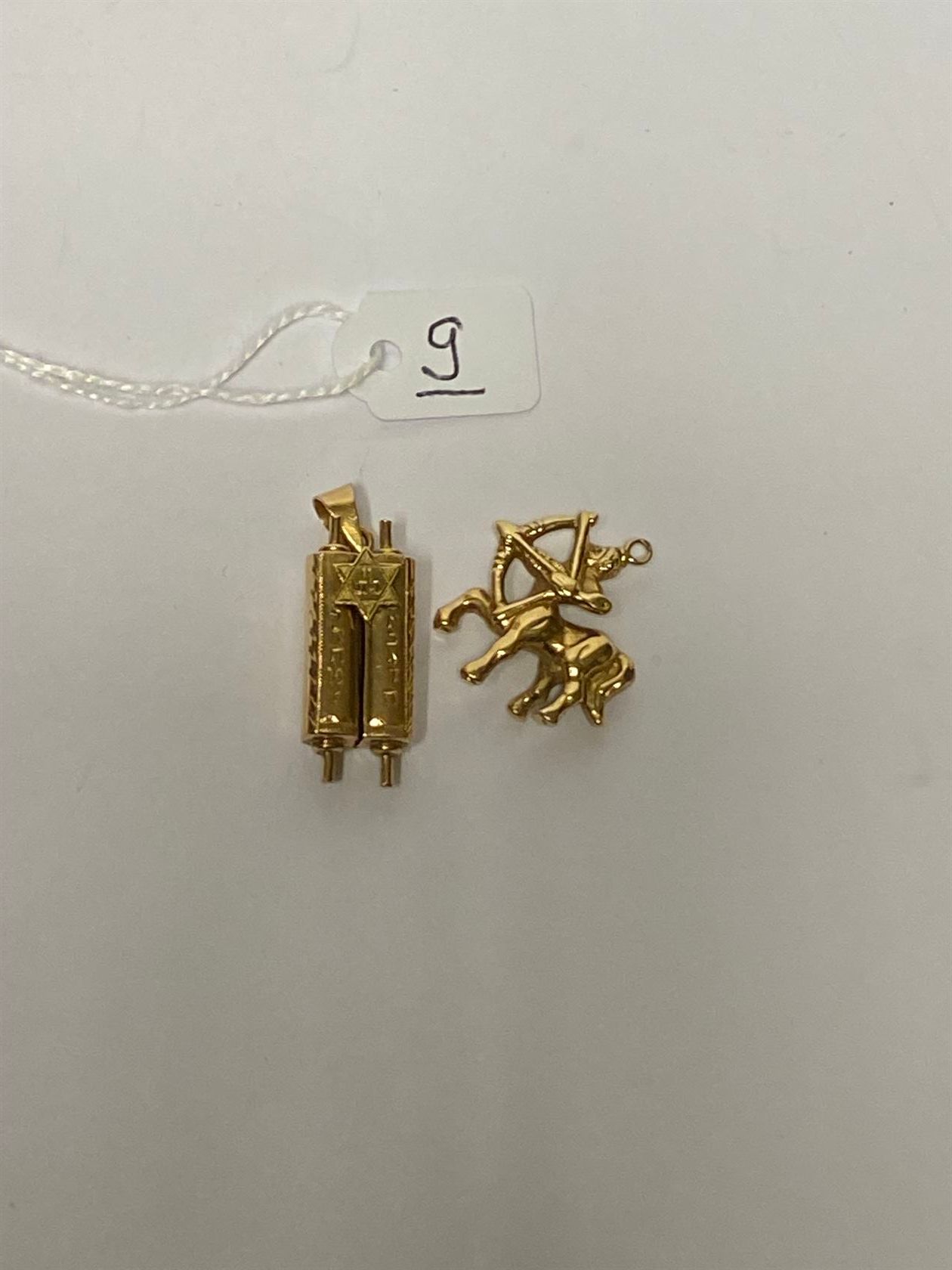 Null 一组两个18K（750千分之一）黄金吊坠。一个有 "半人马 "的装饰，另一个有 "托拉书卷 "的开口。P. 4,8 g.