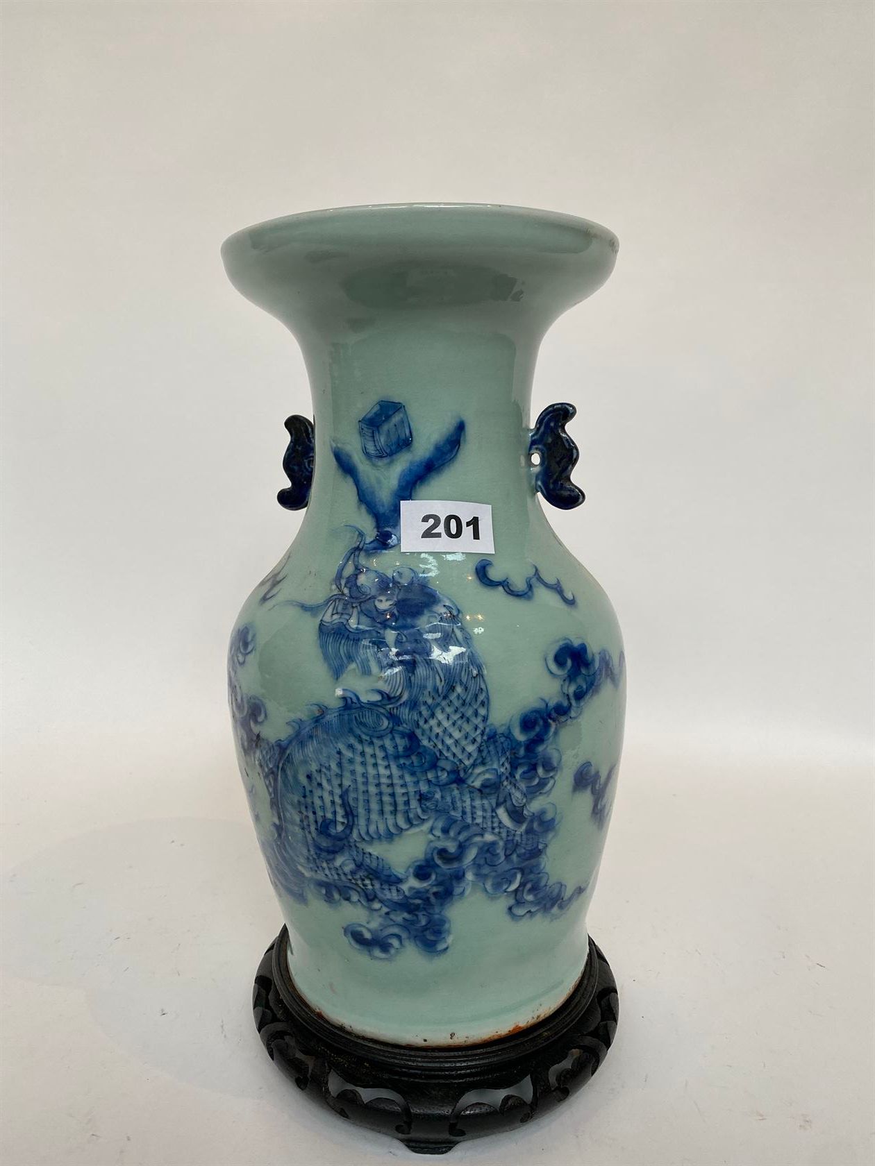 Null 一个青瓷底的阳台花瓶，用蓝色的釉下彩装饰着一只Fô狗，两个蝴蝶形状的把手（底部有裂缝），有一个木制的展示架。中国，20世纪初。高33厘米。