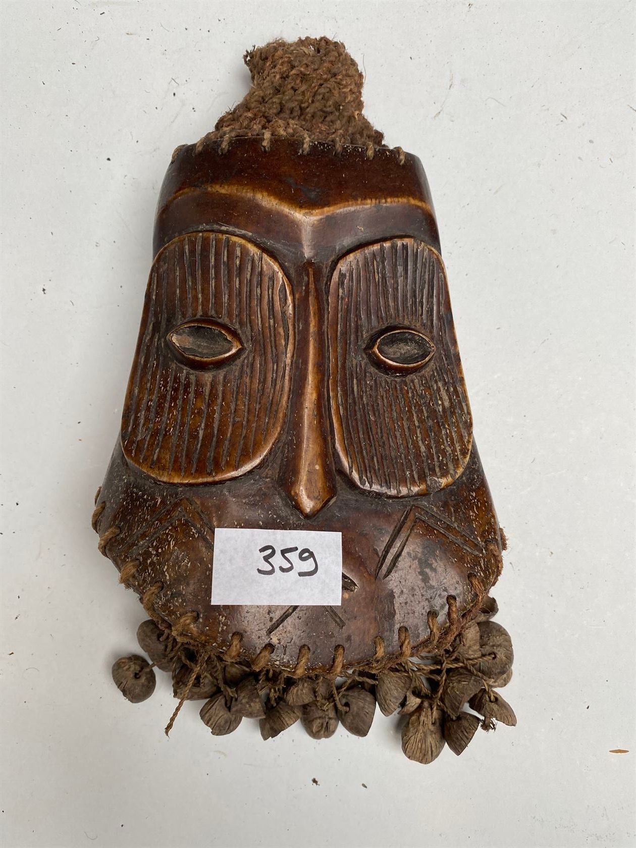 Null 一个杰纳斯类型的骨雕，用种子和纤维代表一个人的面具。20世纪中期。LEGA, 刚果民主共和国。高18厘米。