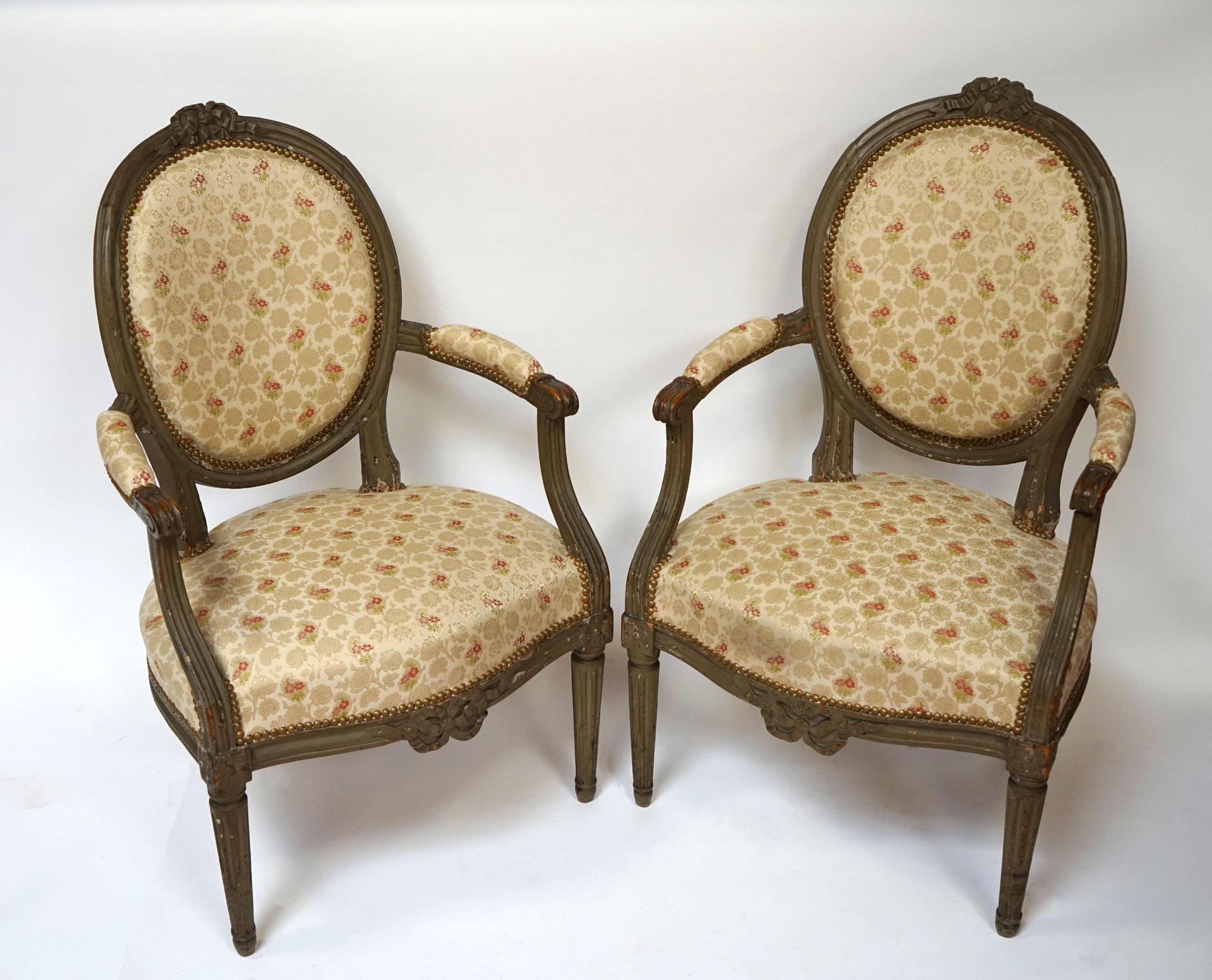 Null 一对灰色的木雕扶手椅，有凹槽的腿，徽章式的卡布丽亚背，腰带上有丝带蝴蝶结装饰。路易十六时期。轻微事故。