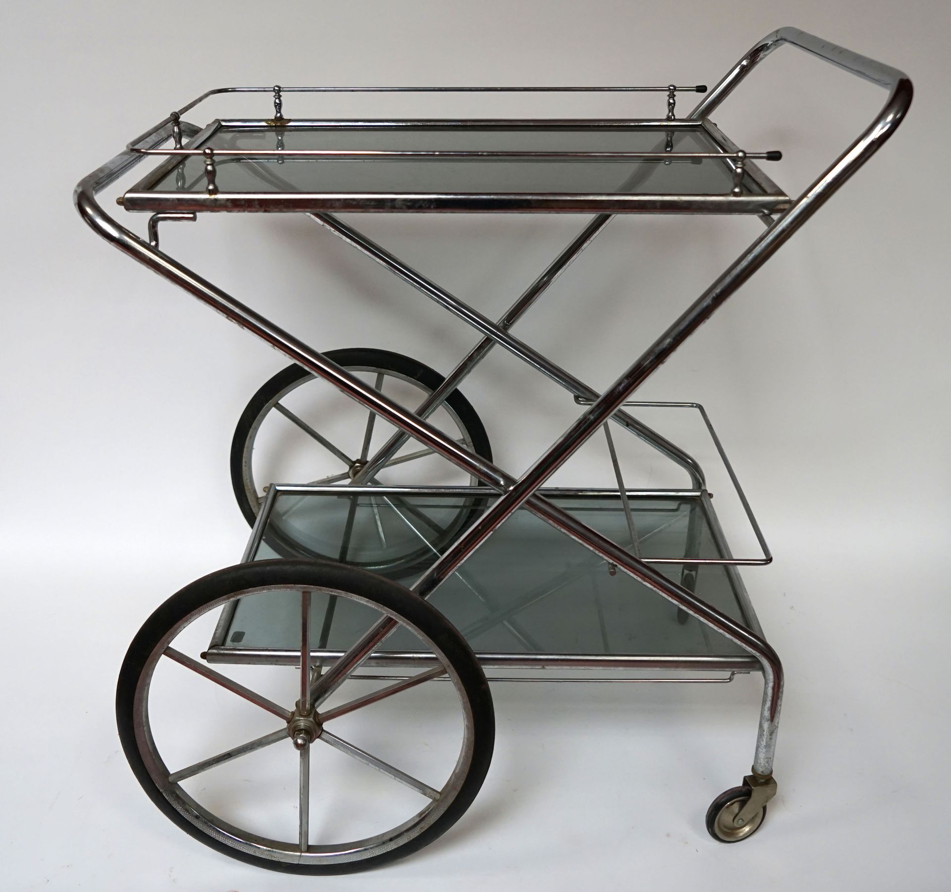 Null 带有两个轮子的镀铬金属折叠茶桌和两个烟熏玻璃托盘。约1950年。轻微划痕。75 x 70 x 40厘米。
