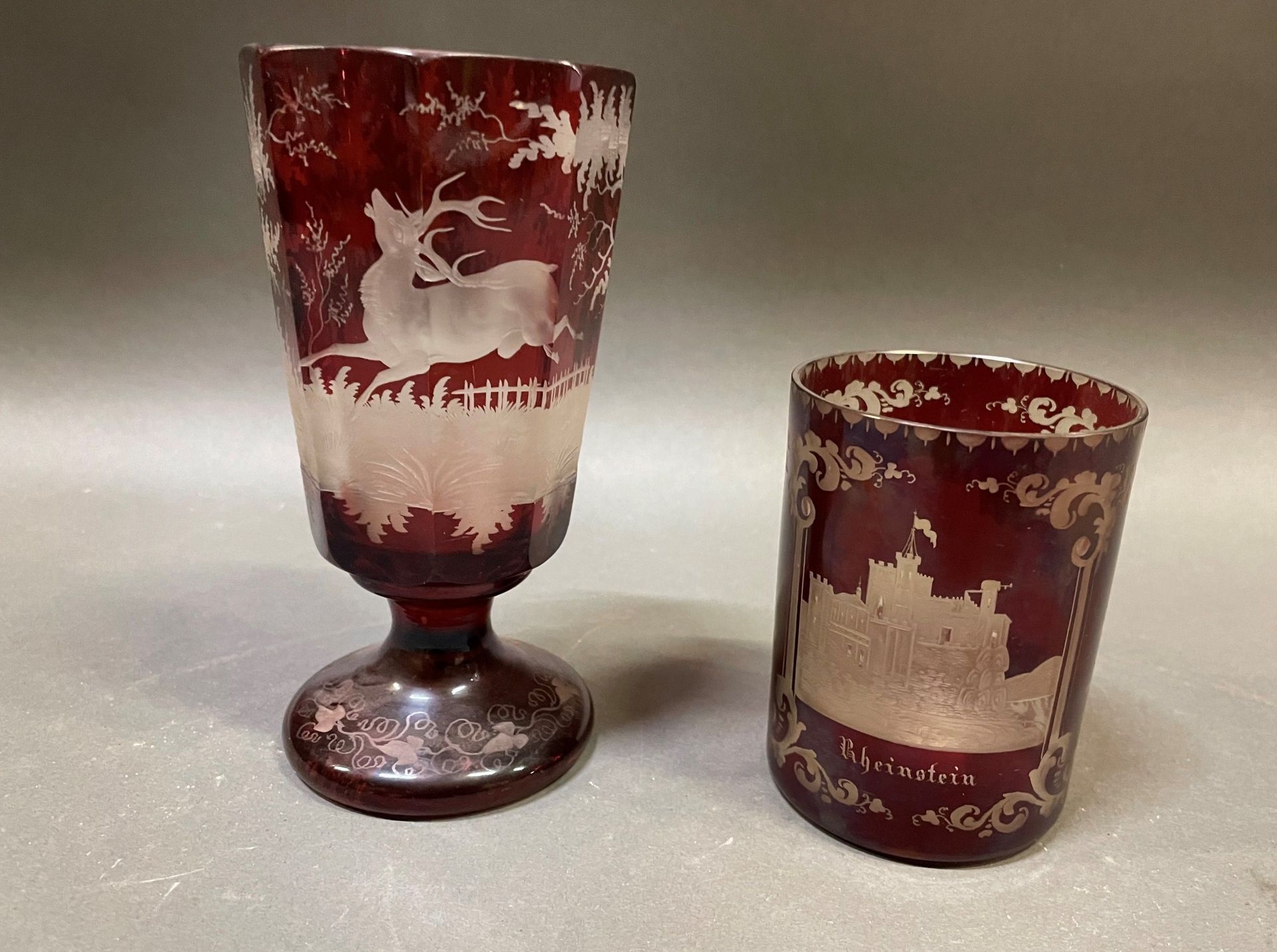 Null 一件波西米亚红色水晶拍品包括：一个底座上的玻璃杯，上面刻有森林中的雄鹿装饰。高度：15.5厘米。15.5厘米，一个刻有城堡装饰的高脚杯，标有RHEIN&hellip;