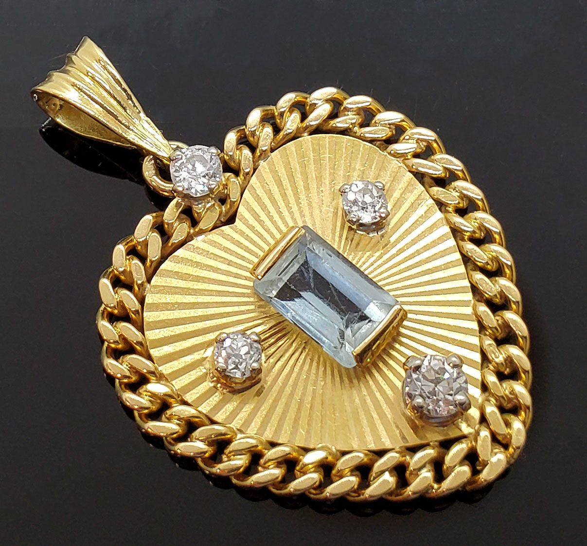 Null 
辐射状的黄金心形吊坠，中间镶嵌着一颗长方形的海蓝宝石，由四颗明亮式切割的钻石加强。