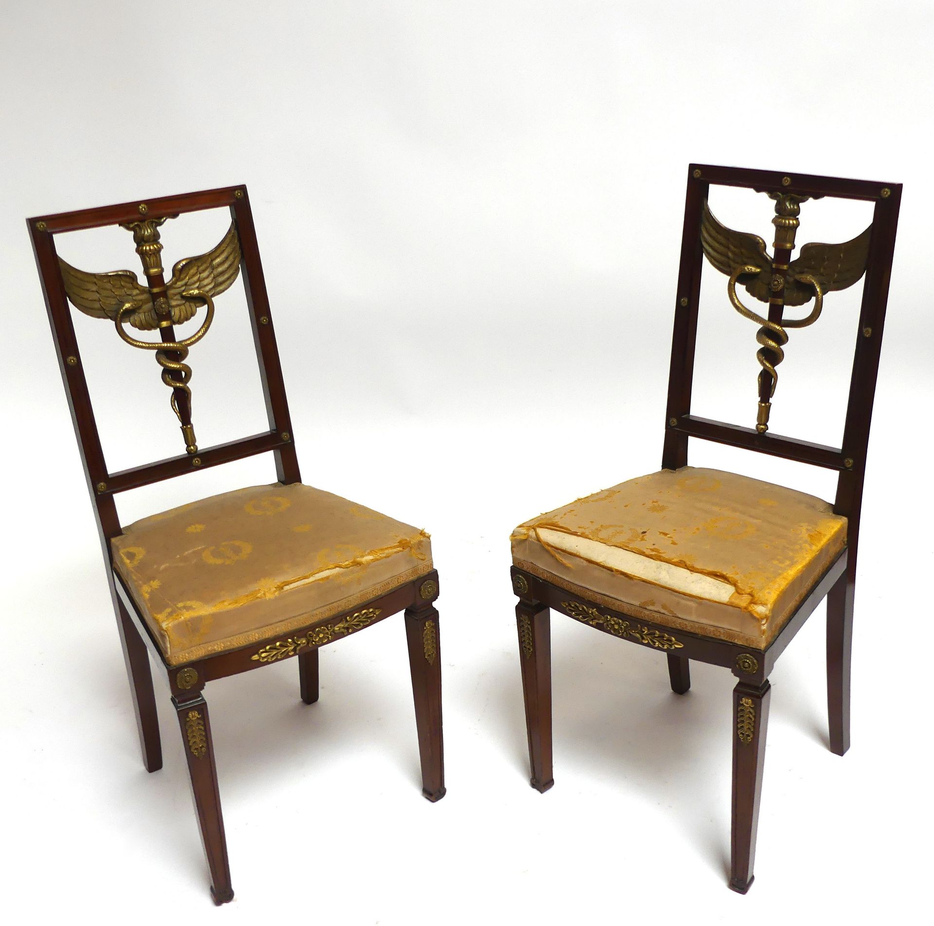 Null 一对桃花心木椅子，靠背上装饰着火炬和两条缠绕在一起的蛇，有镀金的翅膀和镀金的青铜贴纸。帝国风格。