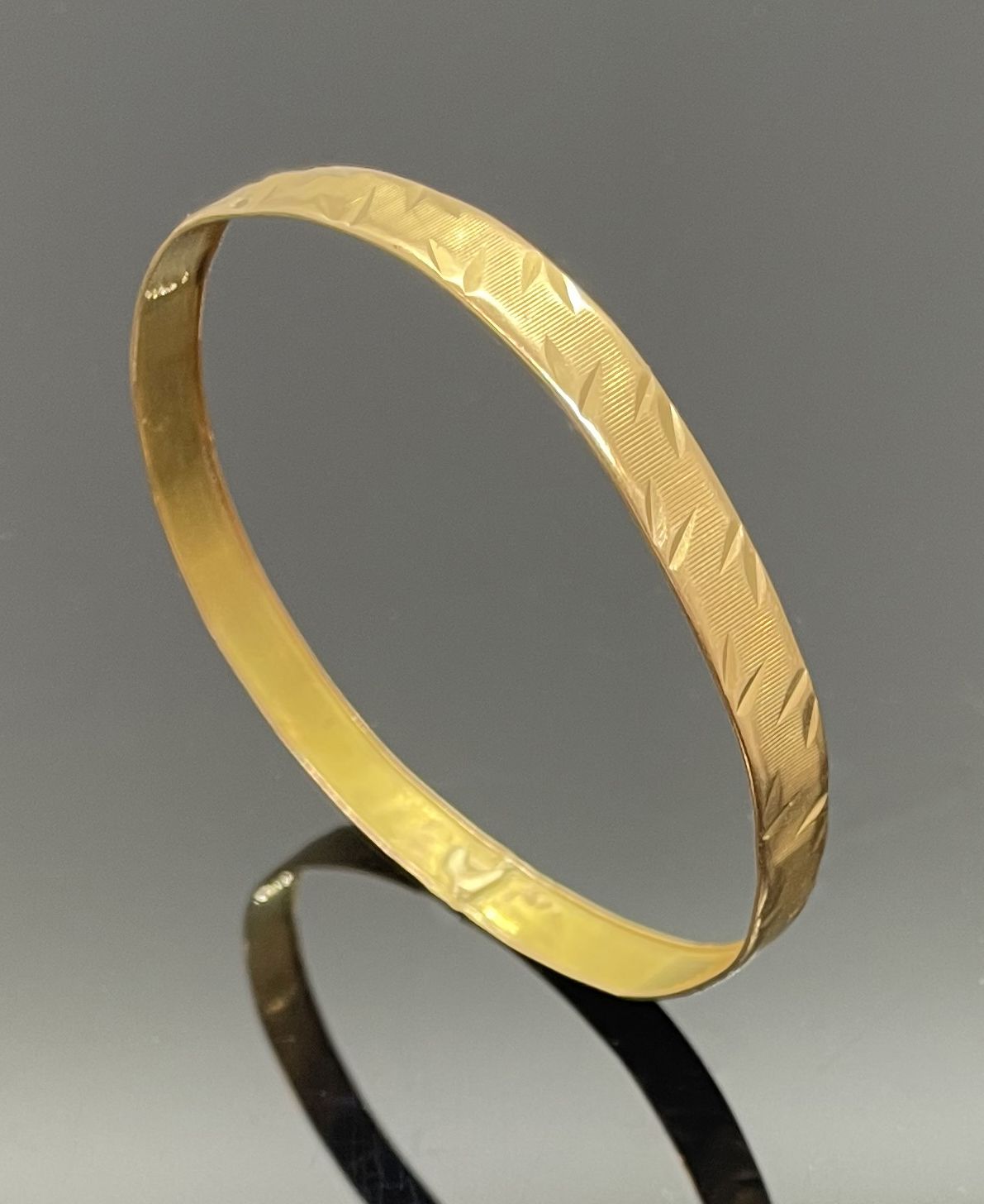 Null 黃金剛性手鏈，條紋背景上有扭索狀圖案。重量：10.96克 直径：6.5厘米（震）。