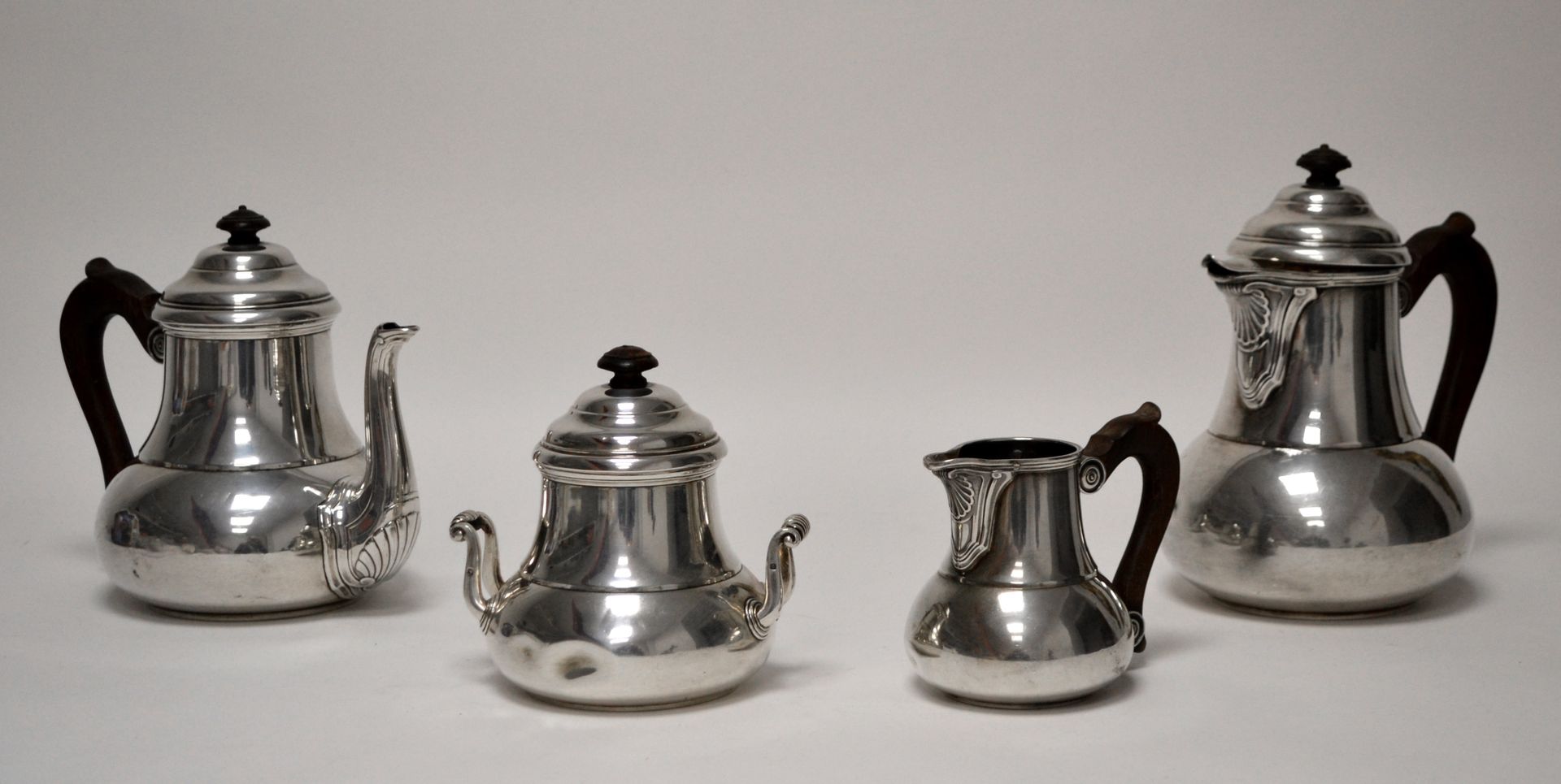 Null 一套银质和木质的茶具和咖啡具，包括一个茶壶，一个咖啡壶，一个奶壶（震惊）和一个水壶，都是柱状的，木质的把手和手柄，壶嘴下有贝壳，有平底，950毫米处有&hellip;