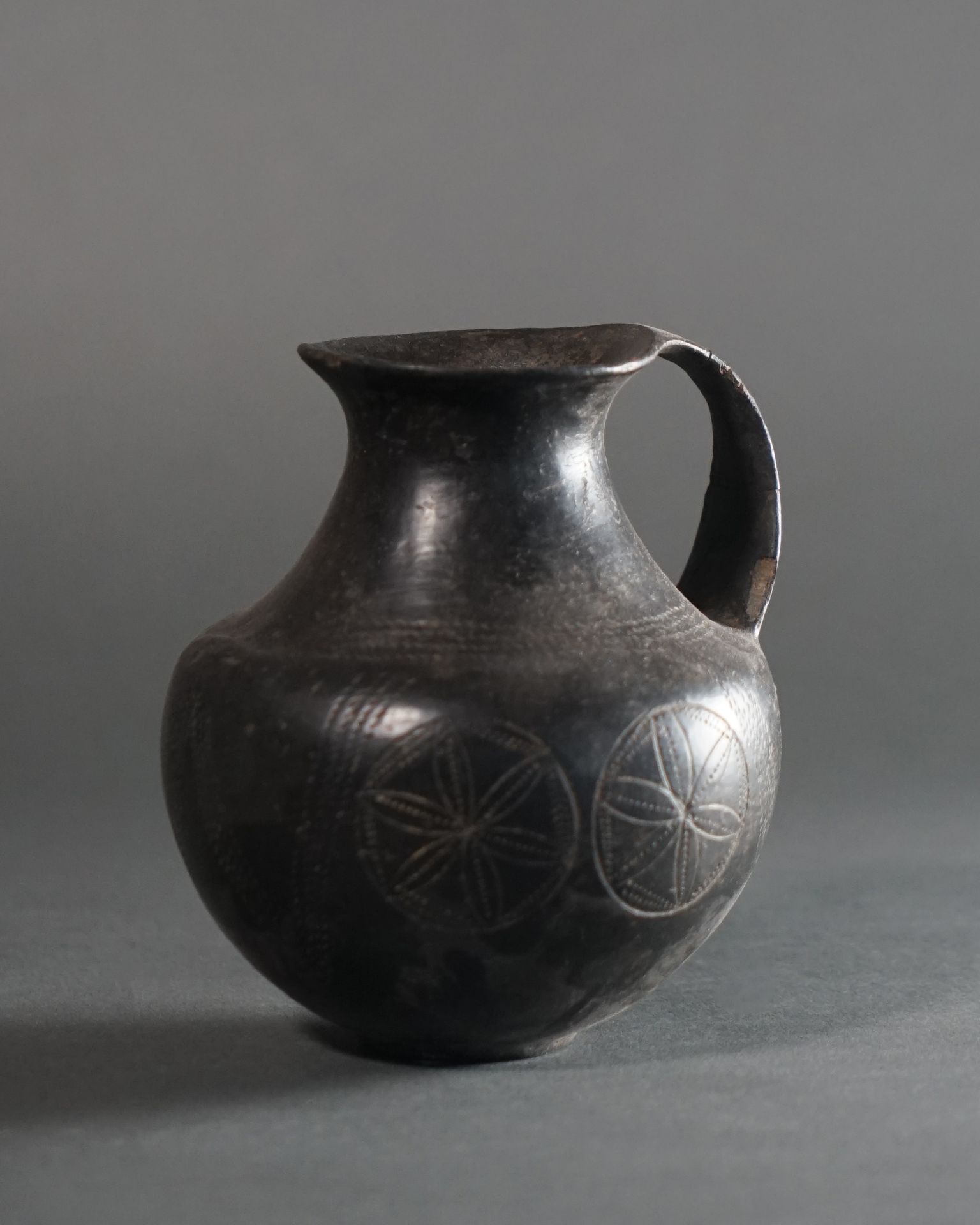 Null JUG with globular body and wide handle. It is incised with six-spoked wheel&hellip;