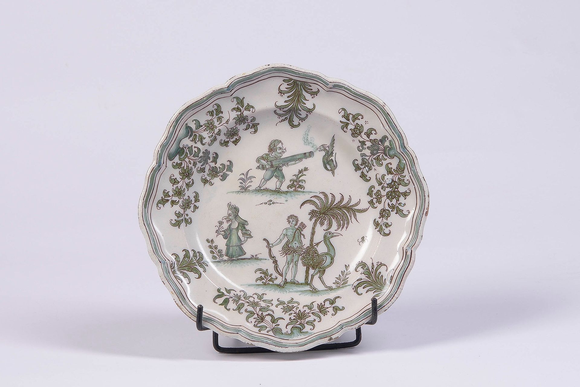 Null MOUSTIERS 绿色单色装饰的陶盘，上面有喜剧人物、龙和鸵鸟，署名Olerys Laugier，18世纪

D: 24 cm

(边缘有磨损的搪瓷&hellip;