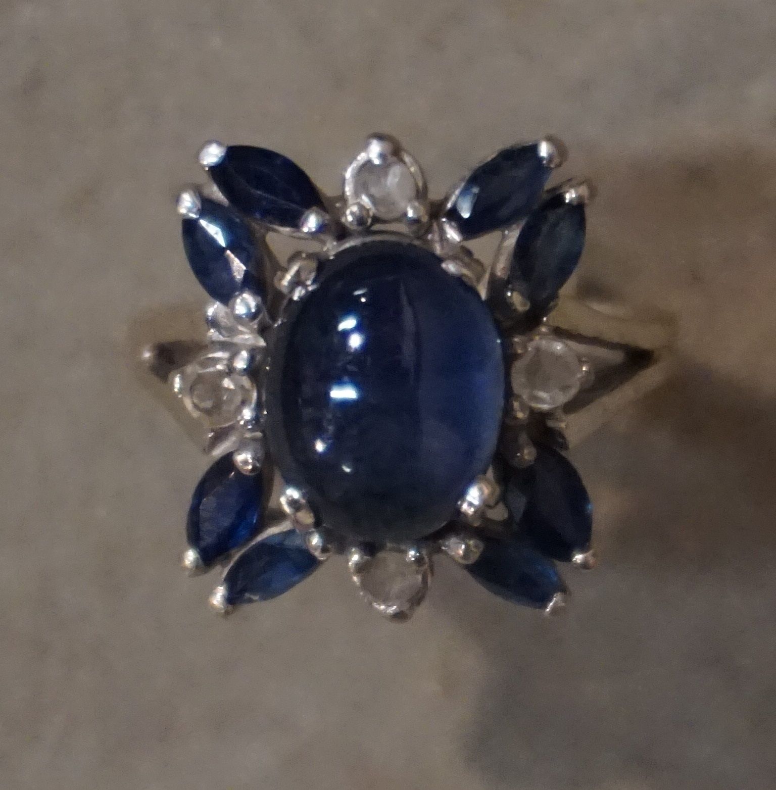 Bague 750千分之一的白金戒指，在一个凸面蓝宝石的中心装饰，周围是形状为脐带的蓝宝石和圆形钻石，切割为8-8或切割为粉红色。手指大小：51。毛重：5.8克