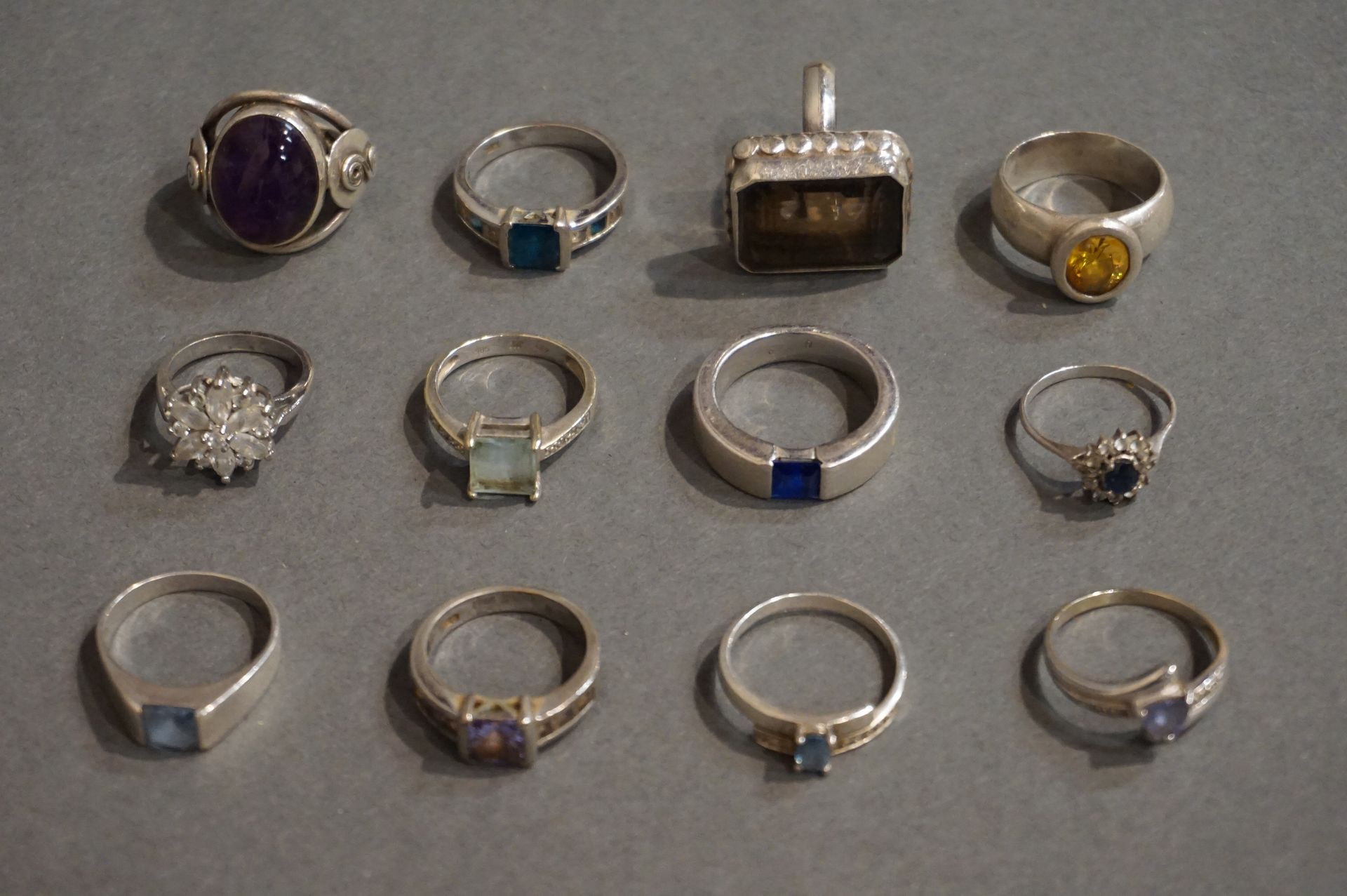 BAGUES 12个银戒指，镶嵌着宝石：一颗蓝宝石，一颗凸面紫水晶等。(总重量：70grs)