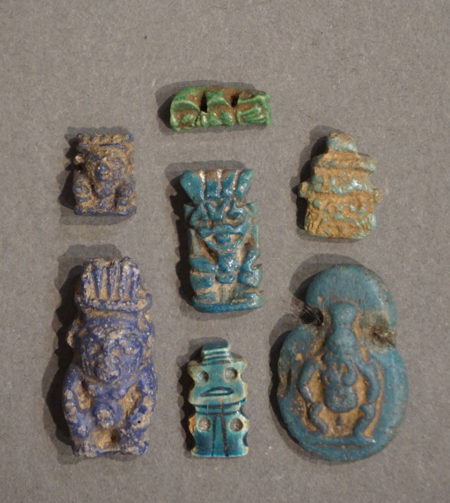 Null 一套七个贝斯神造型的护身符。玻璃浆和陶器。埃及，从第三中间时期到罗马时期。高度：从1.8厘米到3厘米