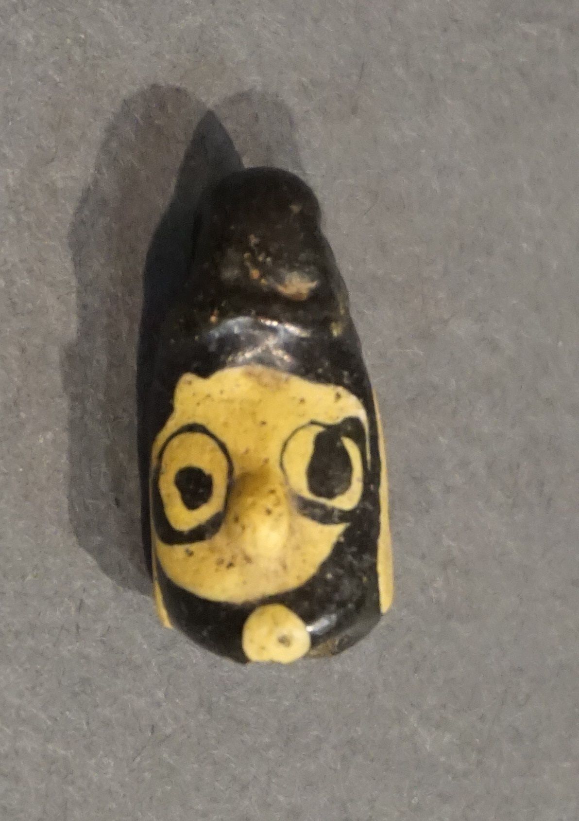 Null Amulet in the form of a janiform head. Yellow and black glass paste. Phoeni&hellip;