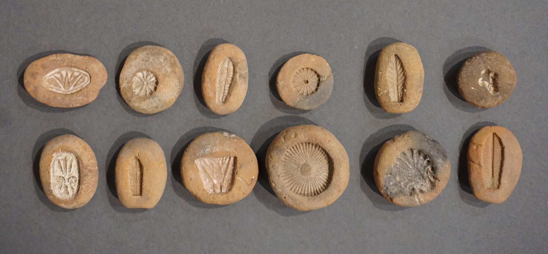 Null 一套12个珠子模具，有植物图案，包括玫瑰花、棕榈花、叶子和莲花。赭色赤土。埃及，新王国至晚期，约公元前1150-332年从3厘米到3.5厘米