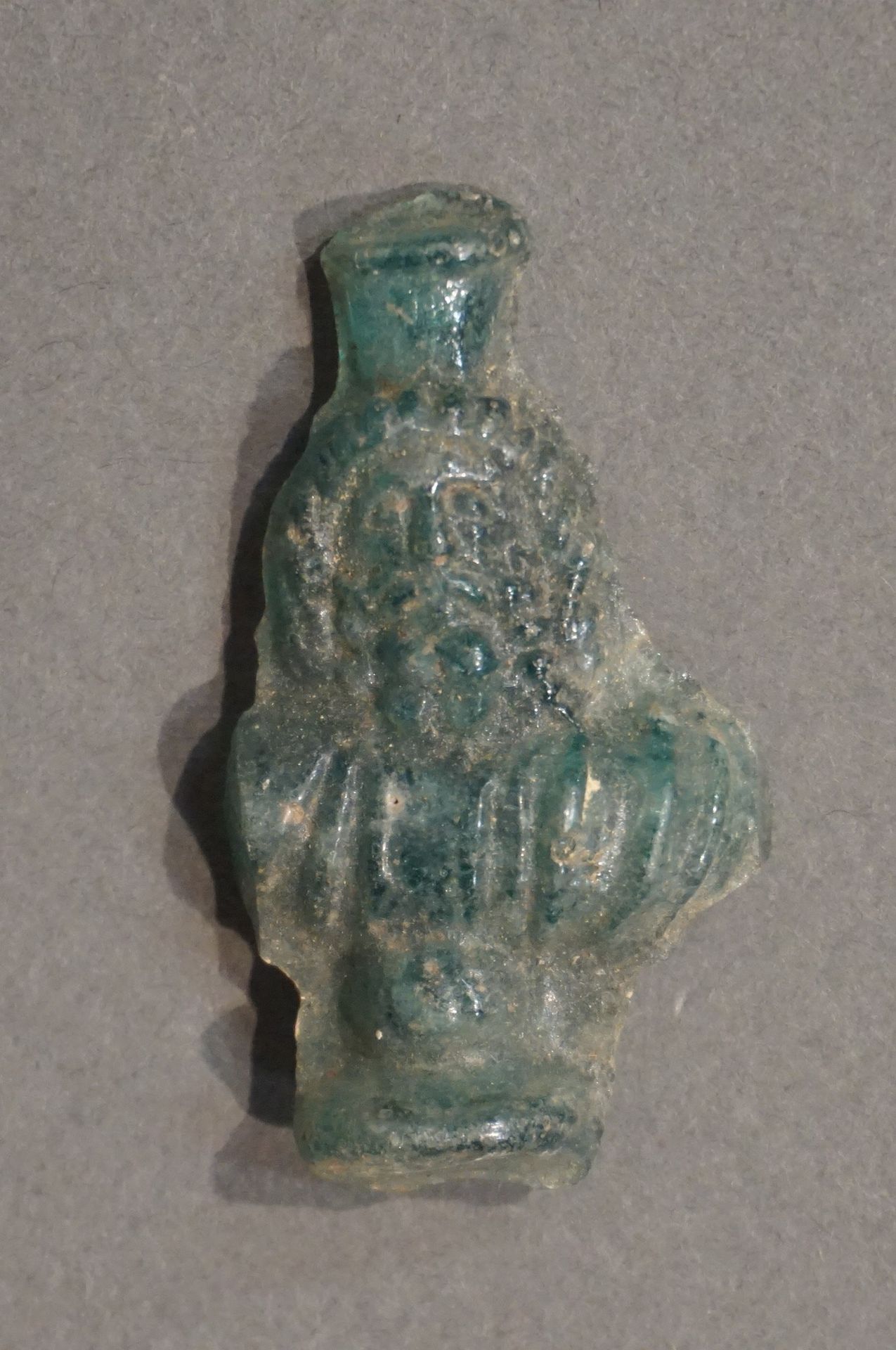 Null 代表萨拉皮斯半身像的模制护身符。半透明的蓝色玻璃。埃及，罗马时期。高度：5.8厘米