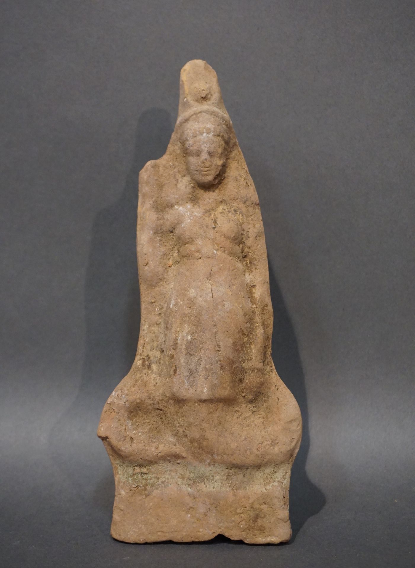 Null 伊希斯-勒内努特/泰尔穆提斯的塑像，身穿腰部收紧的外衣，头戴太阳盘。赭色赤土。右手顶部有小缺口。埃及，罗马时期。高度：20.5厘米