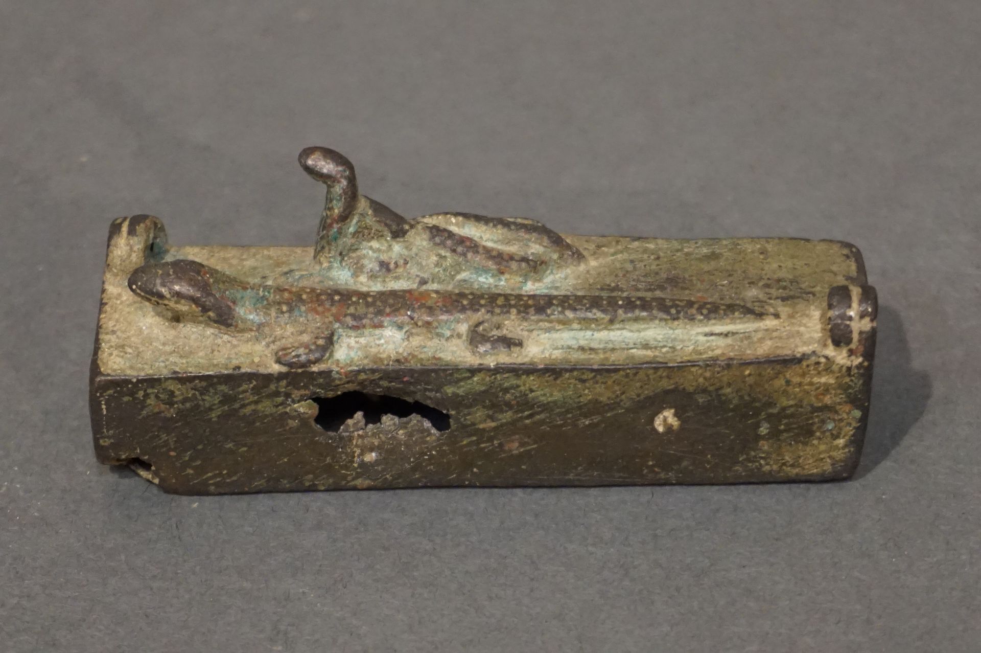 Null 长方形石棺，有两个悬挂支架，代表一只蜥蜴和一只乌拉乌斯盘绕在一起。罕见的图像学。青铜，带有光滑的绿色铜锈。缺少墙壁和盖子。埃及，晚期，公元前664-3&hellip;