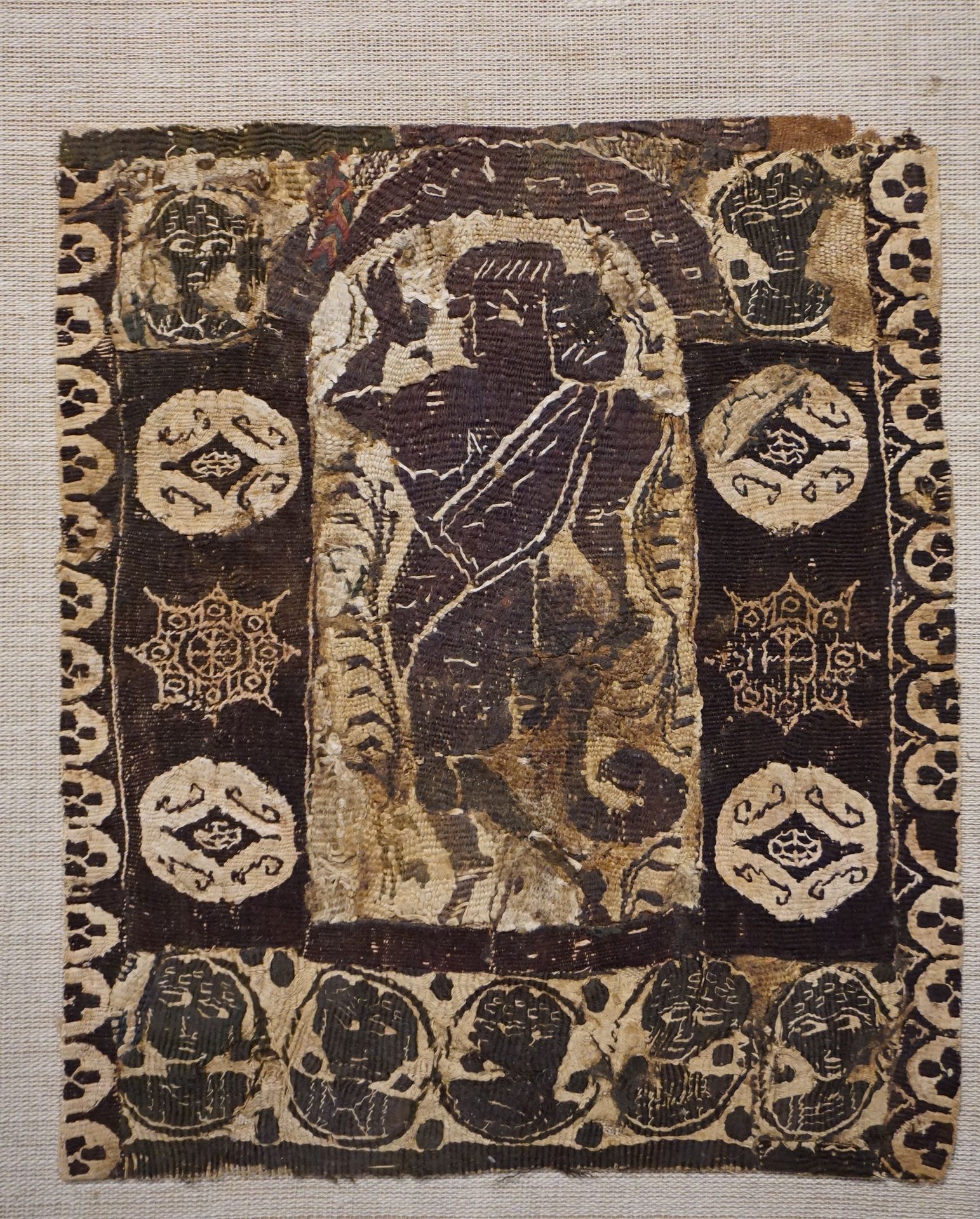 Null 重要的碎片表现了一个在凹室中跳舞的女妖，凹室的框架上有代表人物半身像和几何图案的徽章。棕色亚麻布。事故和污点。埃及，4-6世纪。长：20厘米，宽：23&hellip;