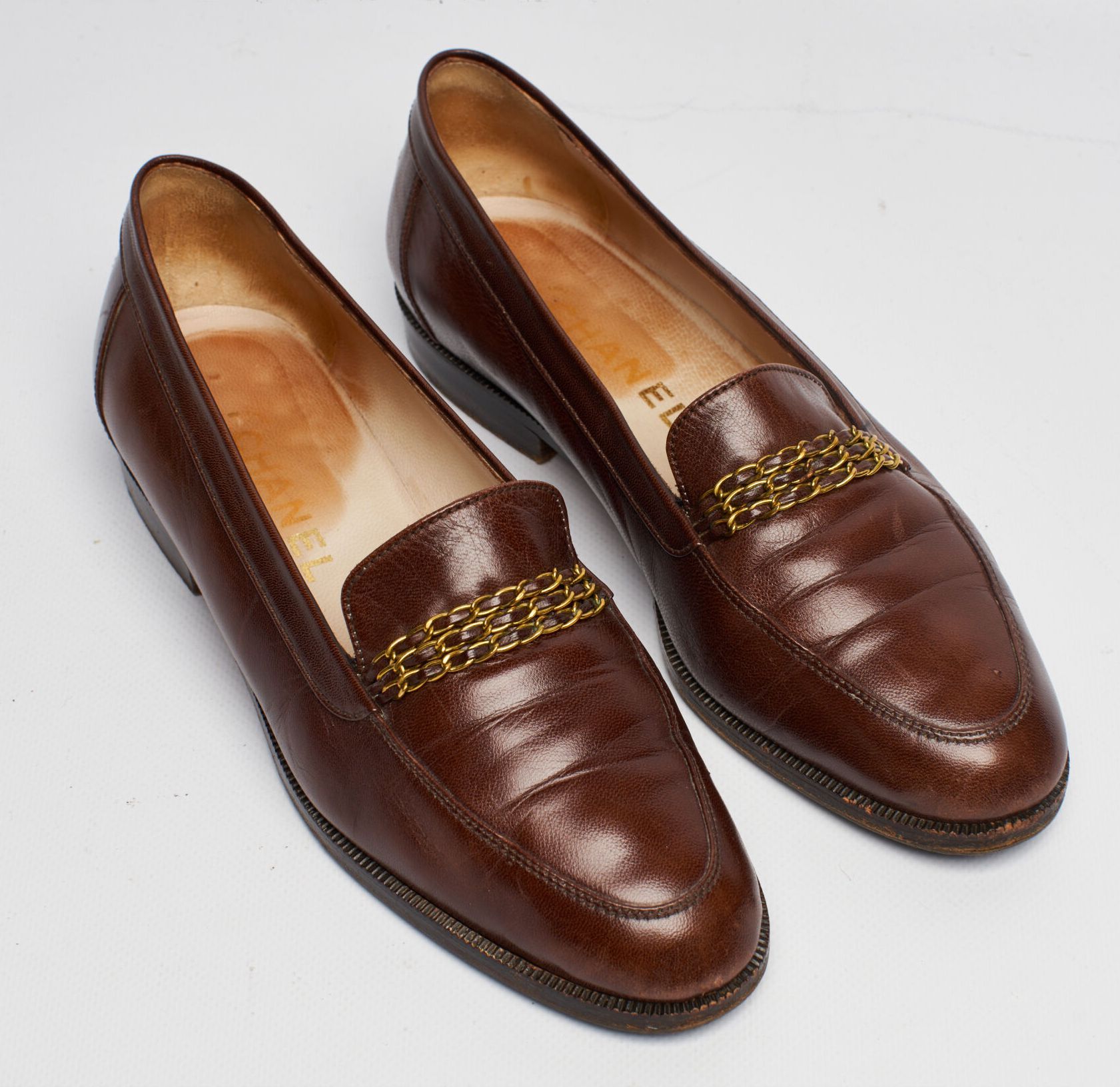CHANEL. Pair of brown leather loafers adorned with inte…