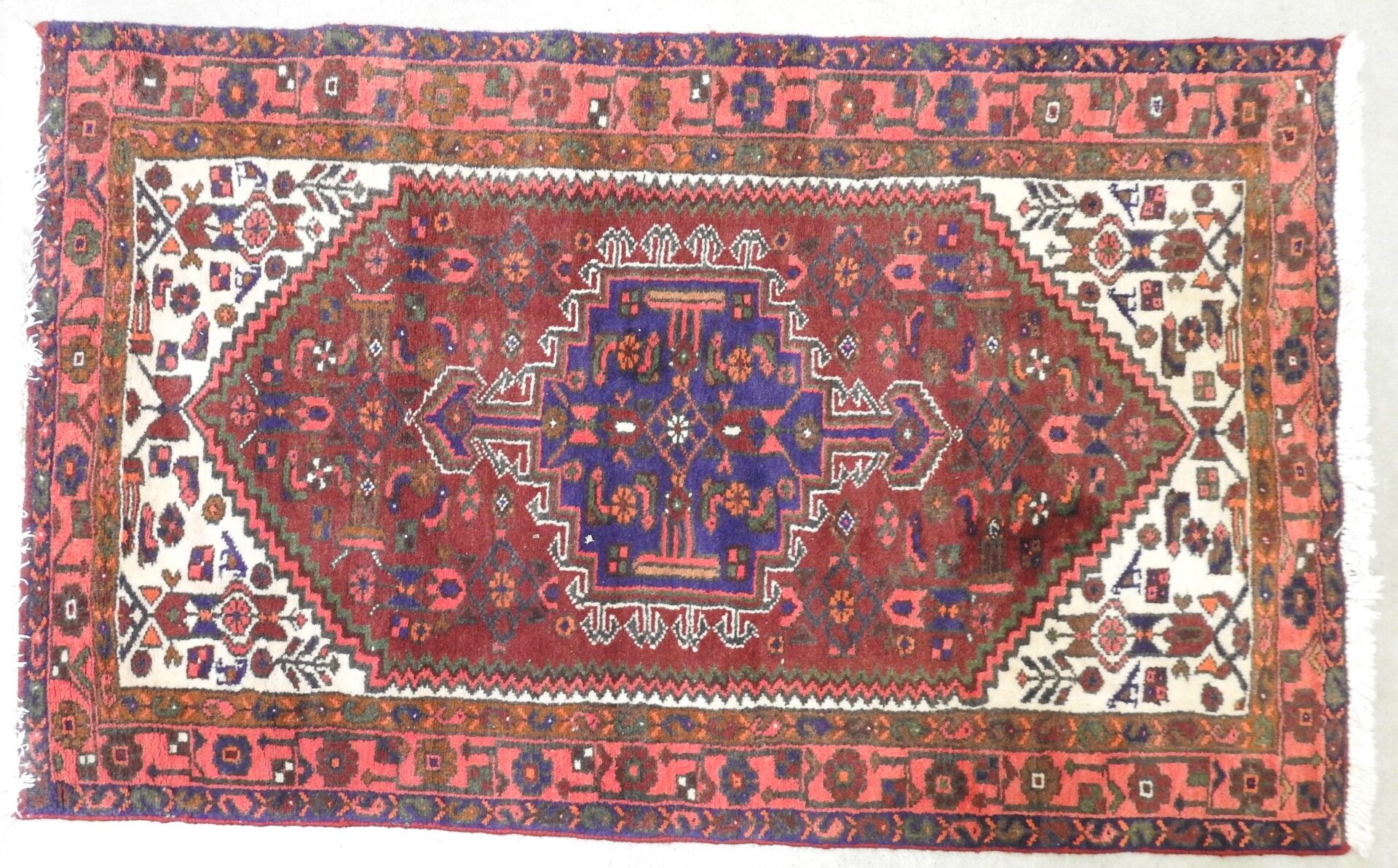 Null TAPIS d'Iran en laine à fond rouge à décor géométrique. 92 x 155 cm.