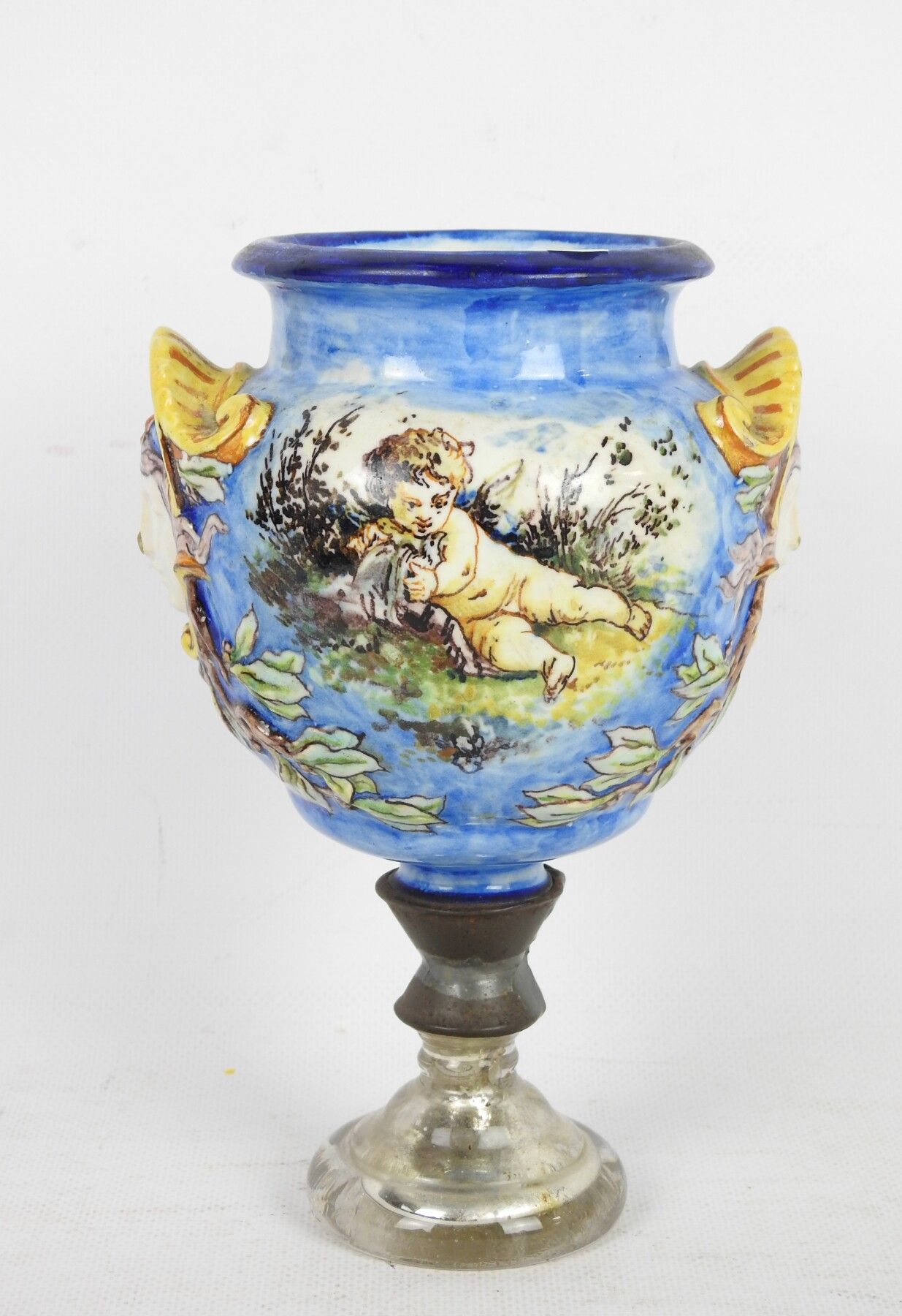 Null 多色陶器小花瓶，装饰有小天使和鸽子，把手形成面具，安装在一个玻璃和金属底座上。高度：20厘米。