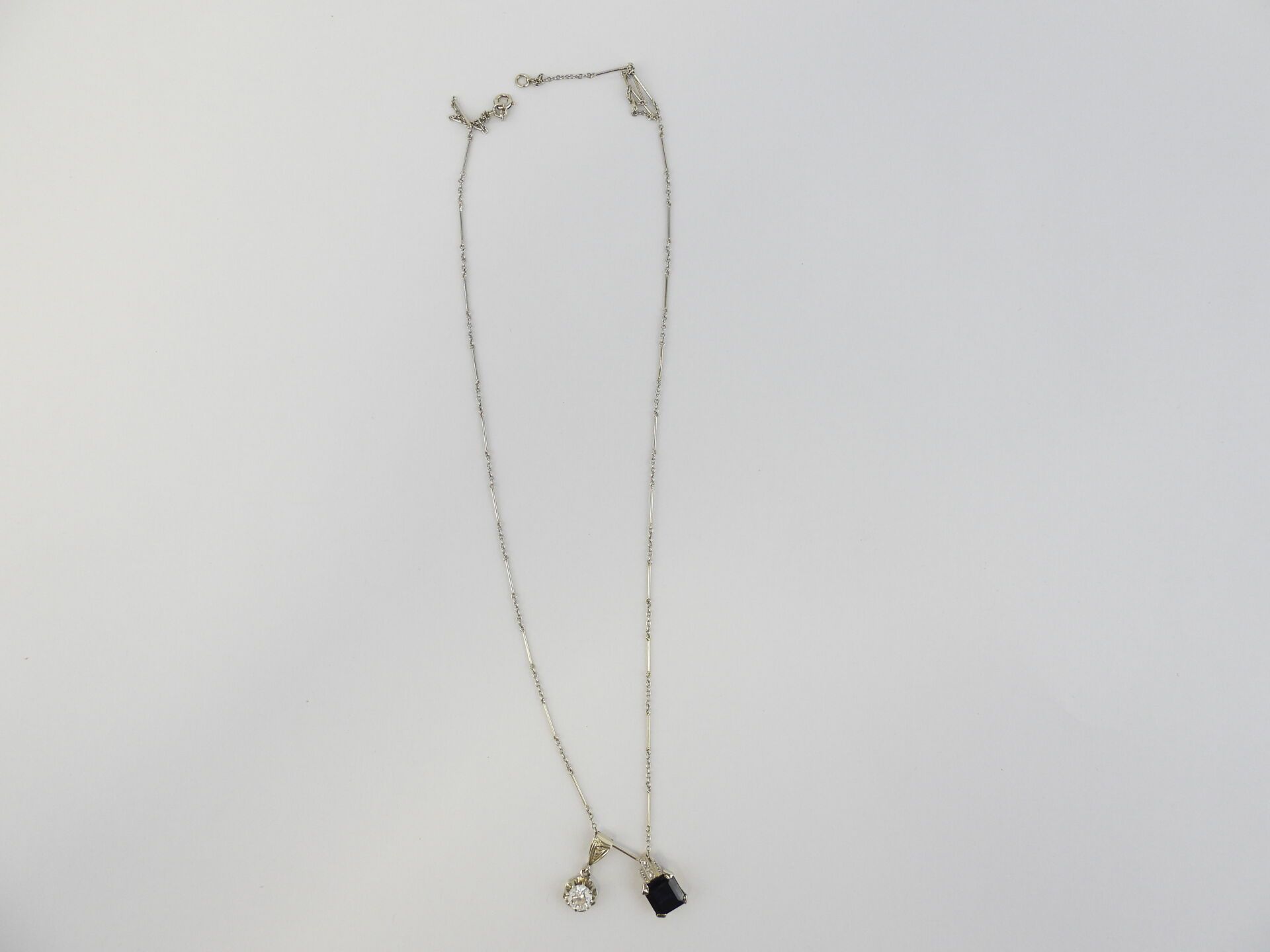Null 白金链，约1克。附有两个带有白色和蓝色宝石的花式吊坠。