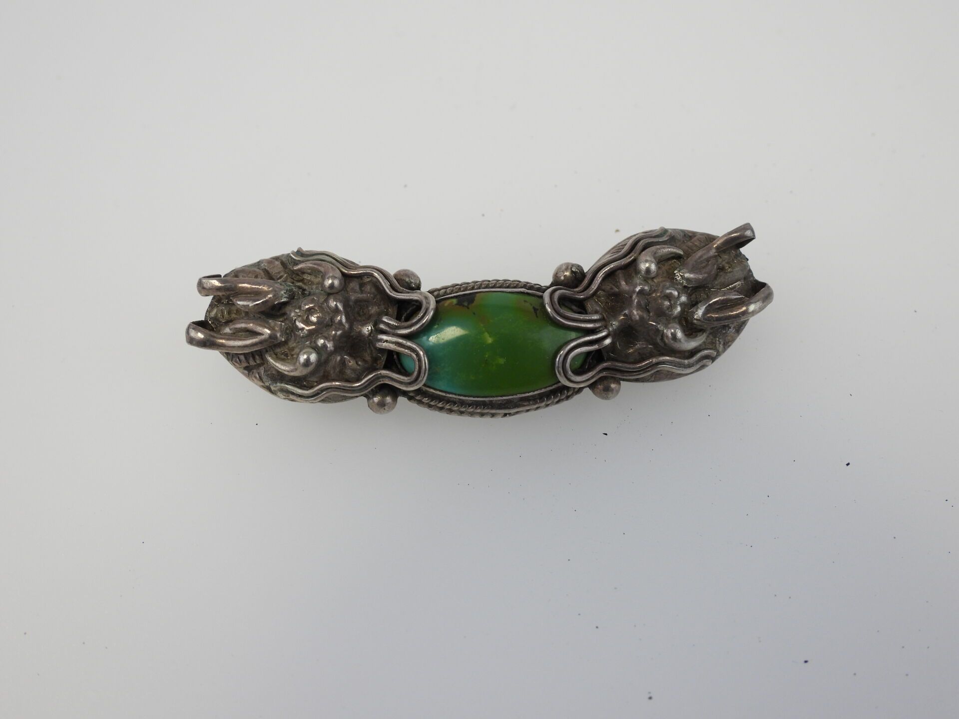 Null Silver brooch decorated with a shaded green stone. 17,85 gr