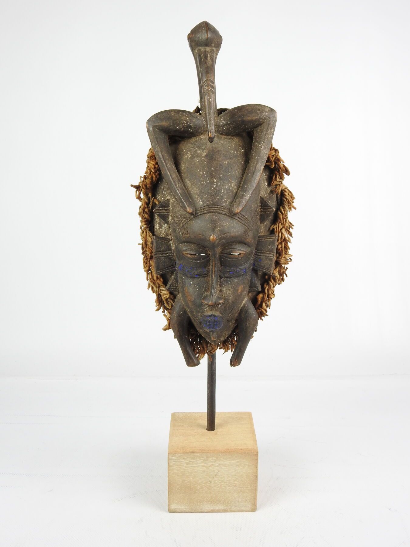 Null 象牙海岸SENOUFO。
木头，黑色铜锈，纤维，靛蓝颜料。
Kpelié "舞蹈面具，脸上有一个犀鸟头。
高度：34厘米。
